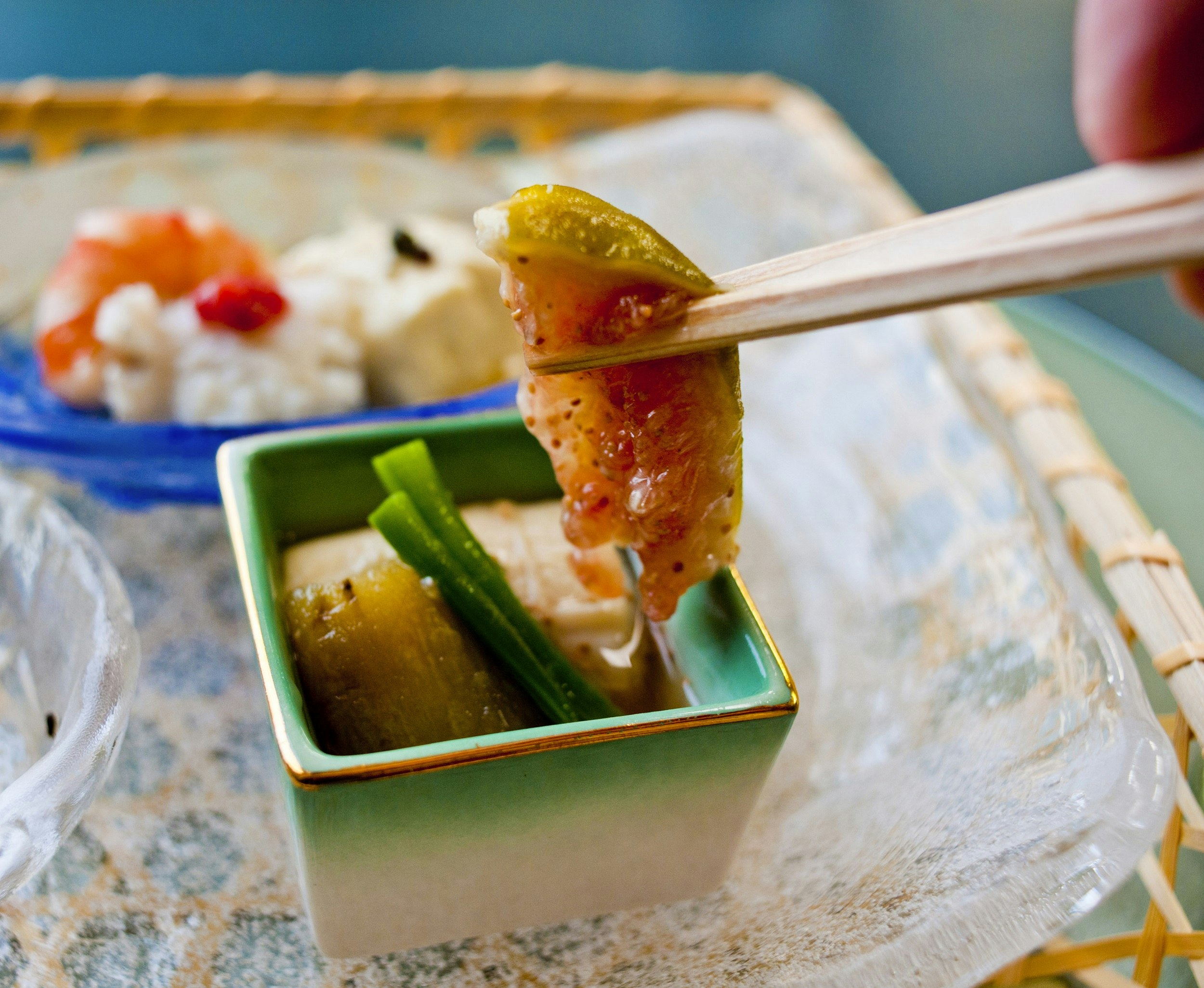 A set of chopsticks holds some traditional Buddhist cuisine, which sits in a small square bowl.