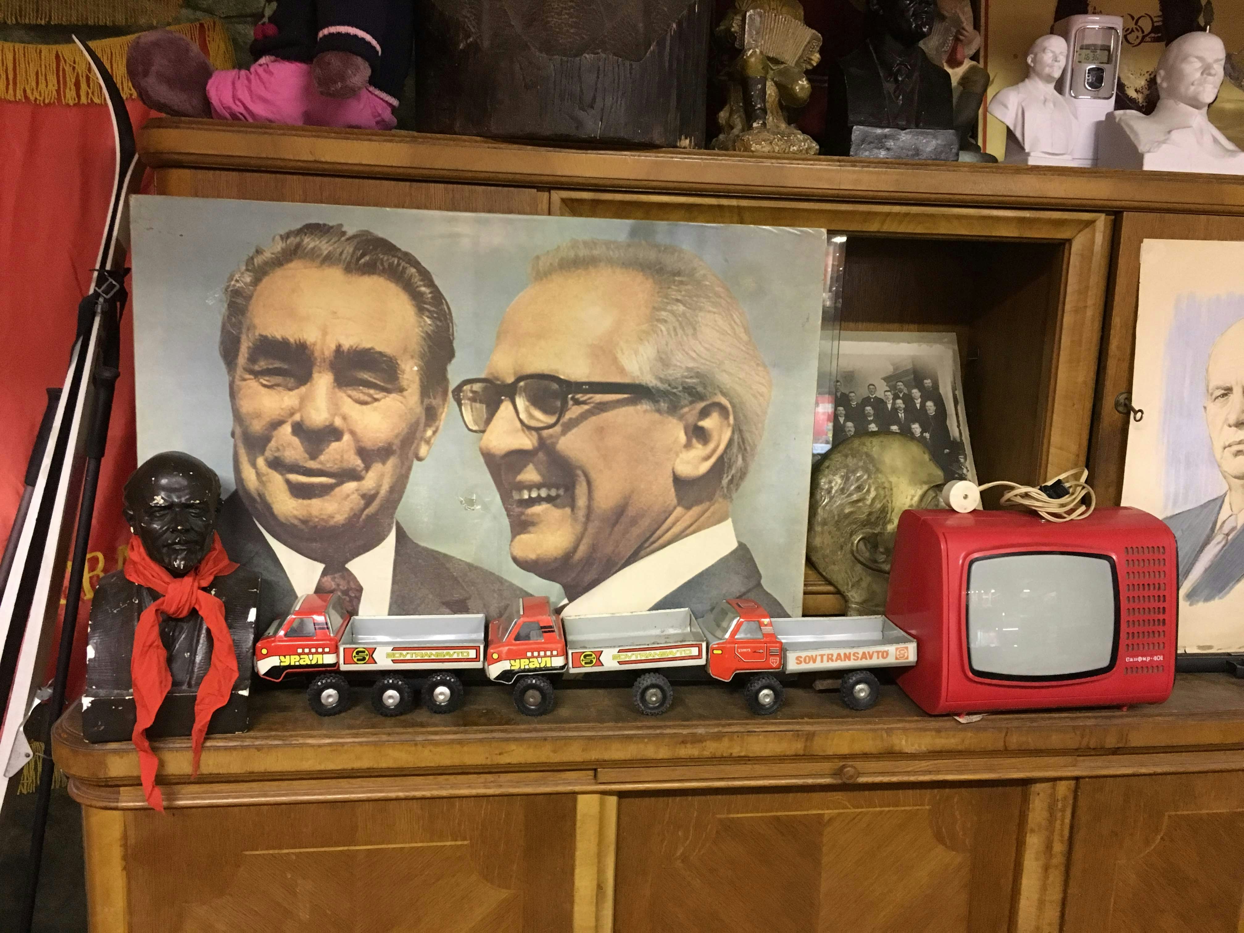 Russian memorabilia including a picture of politicians Brezhnev and Honecker, three small trucks and a bust of Lenin