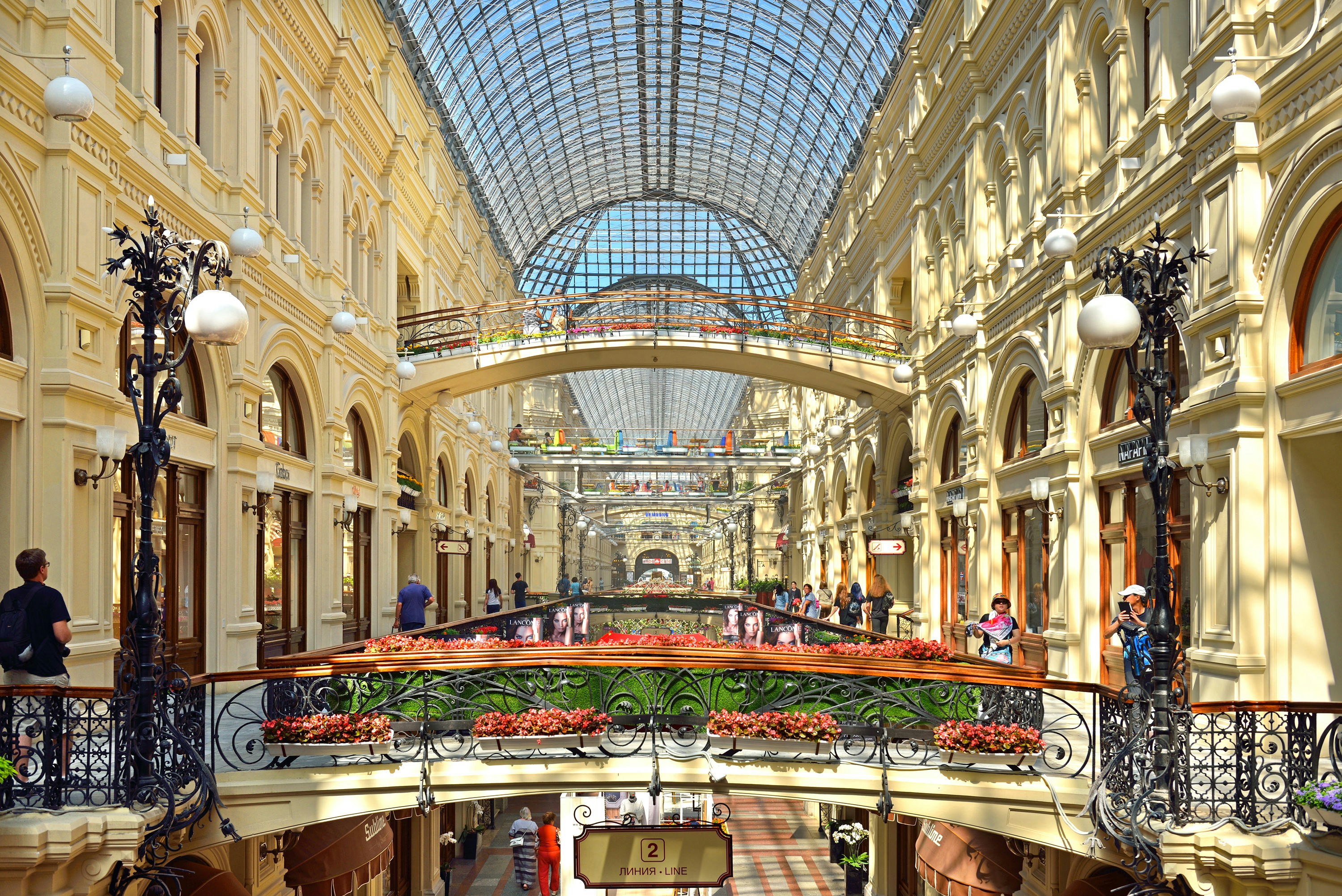 An interior view of a wide open mall, with a domed glass roof above.
