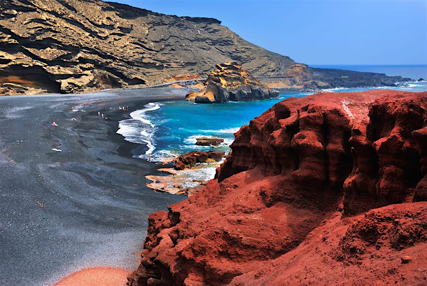 A black-sand beach with vivid red rocks in Lanzarote, Canary Islands