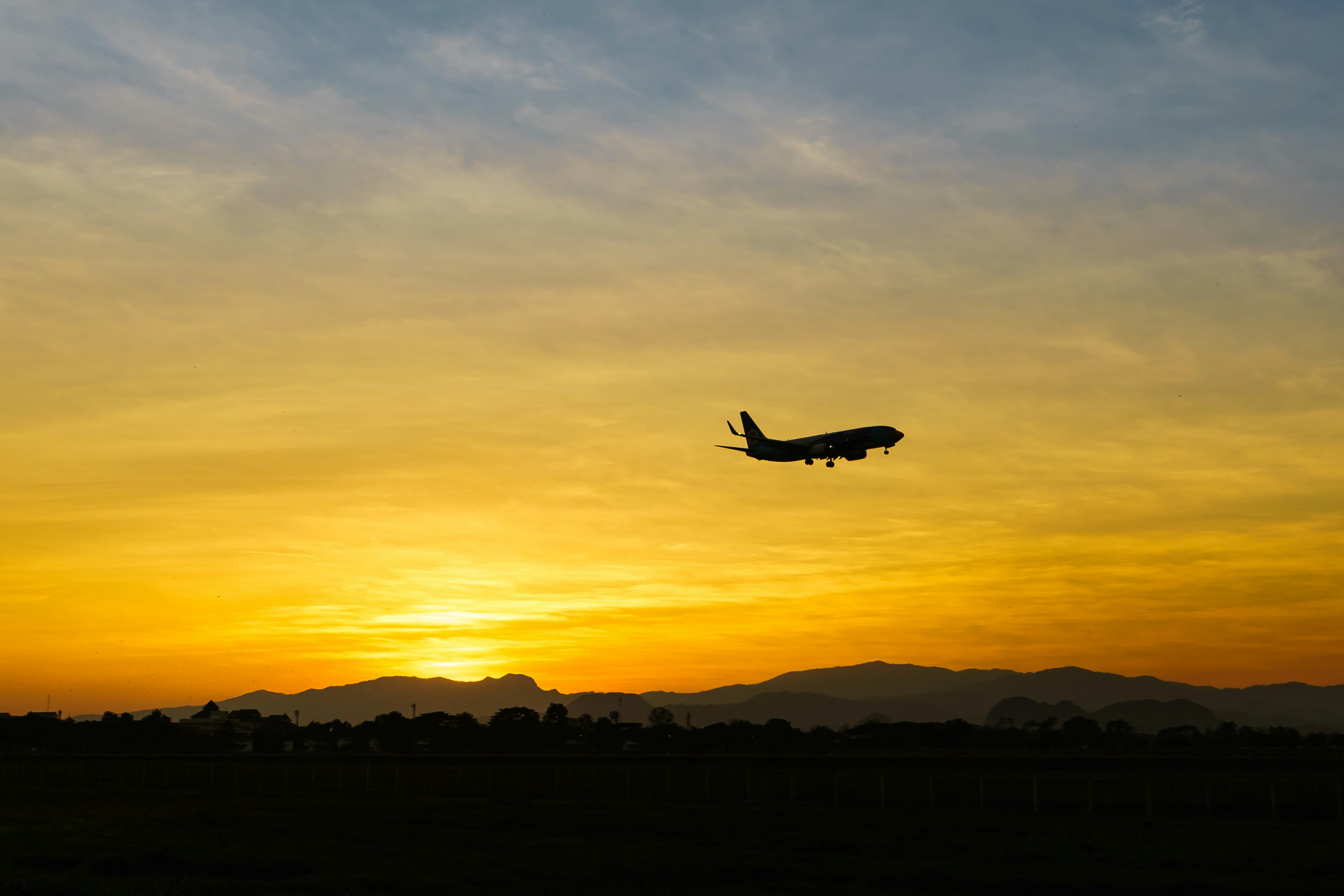 A silhouette of a plane against a bright orange sunset