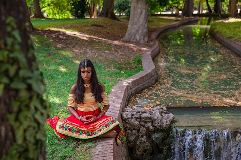 A young Indian woman does yoga outside