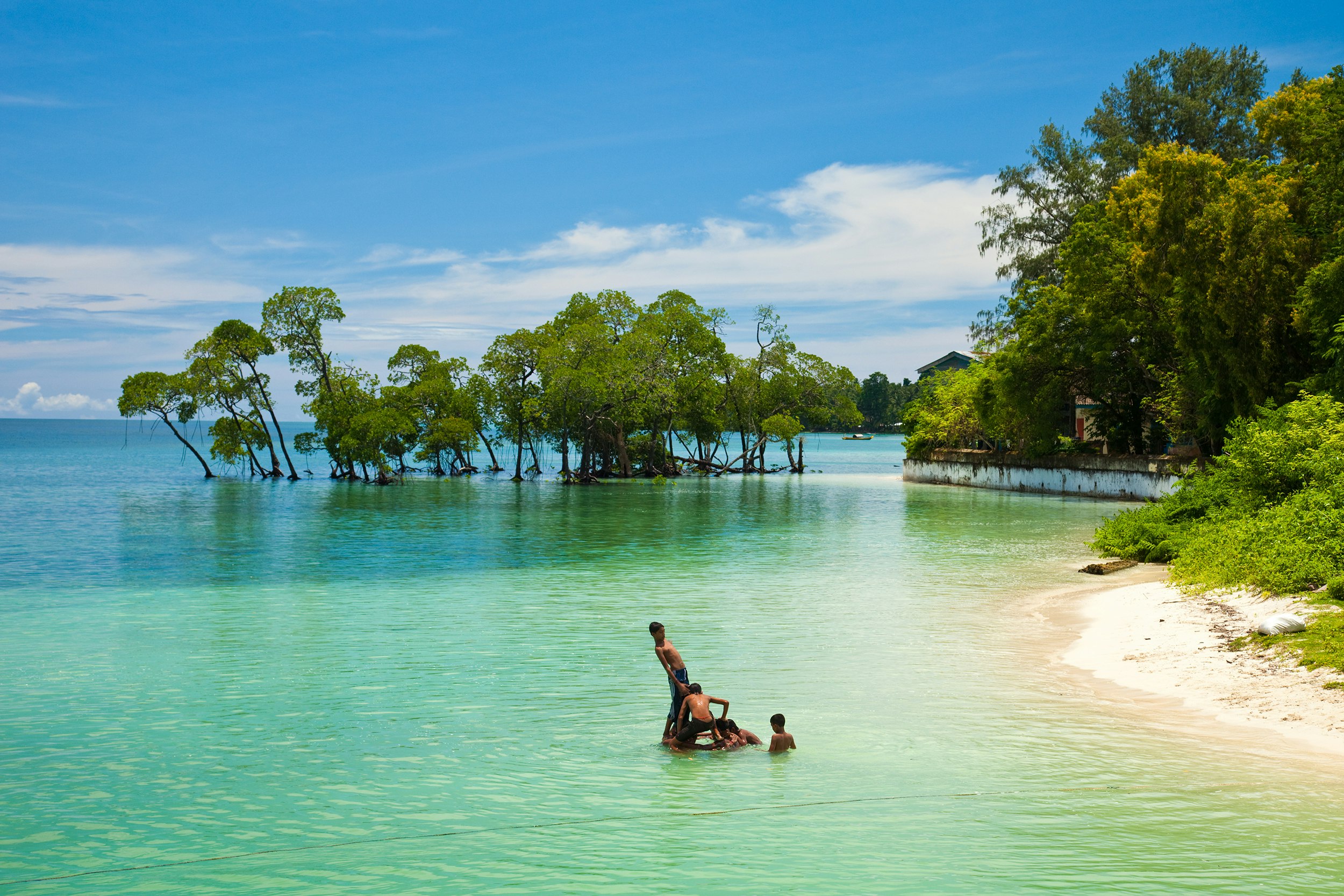 A group of Indian children playing in the shallow turquoise waters near the Havelock Island jetty.