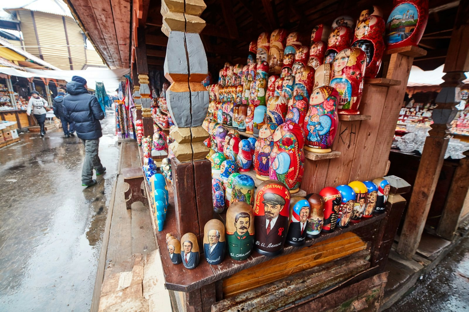 An outdoor stall selling Russian dolls painted in bright reds and blues, some with recognisable figures on them, such as Donald Trump and Marilyn Monroe