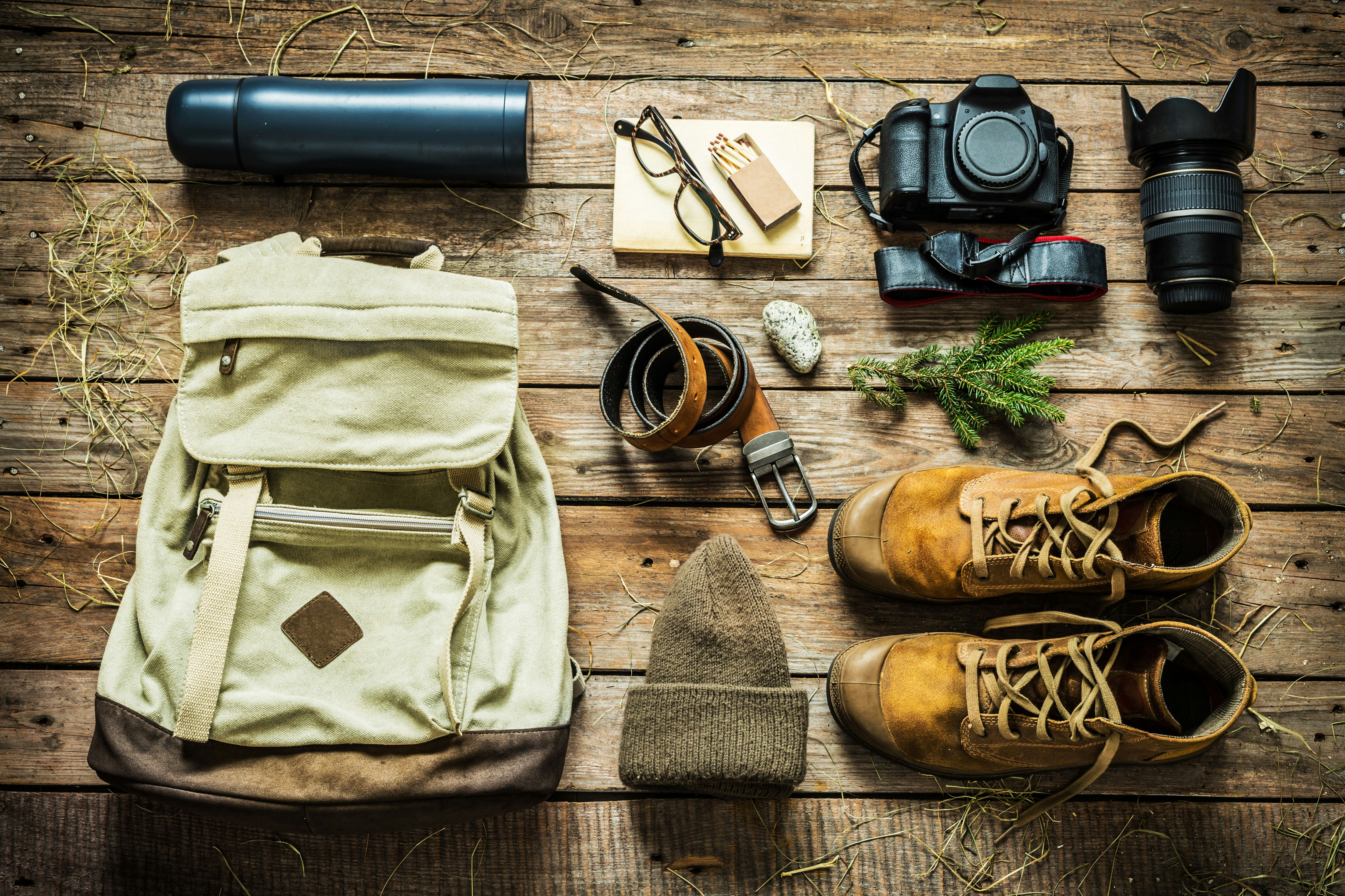Items including boots, a hat, a belt, a thermos and a camera are laid out neatly on a wooden floor, ready to be packed.