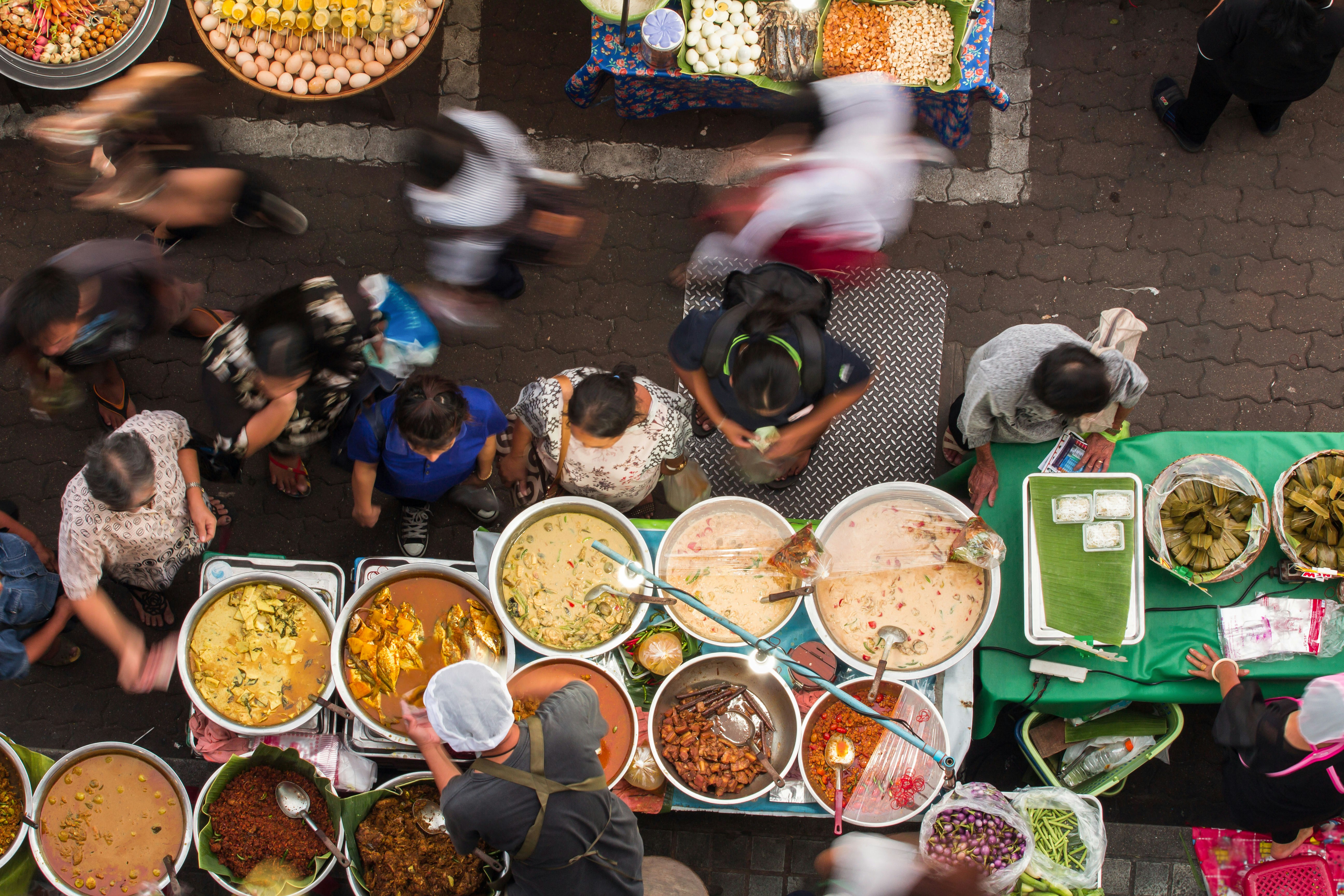 Overhead shot of a market in Bangkok, with street food in large circular bowls