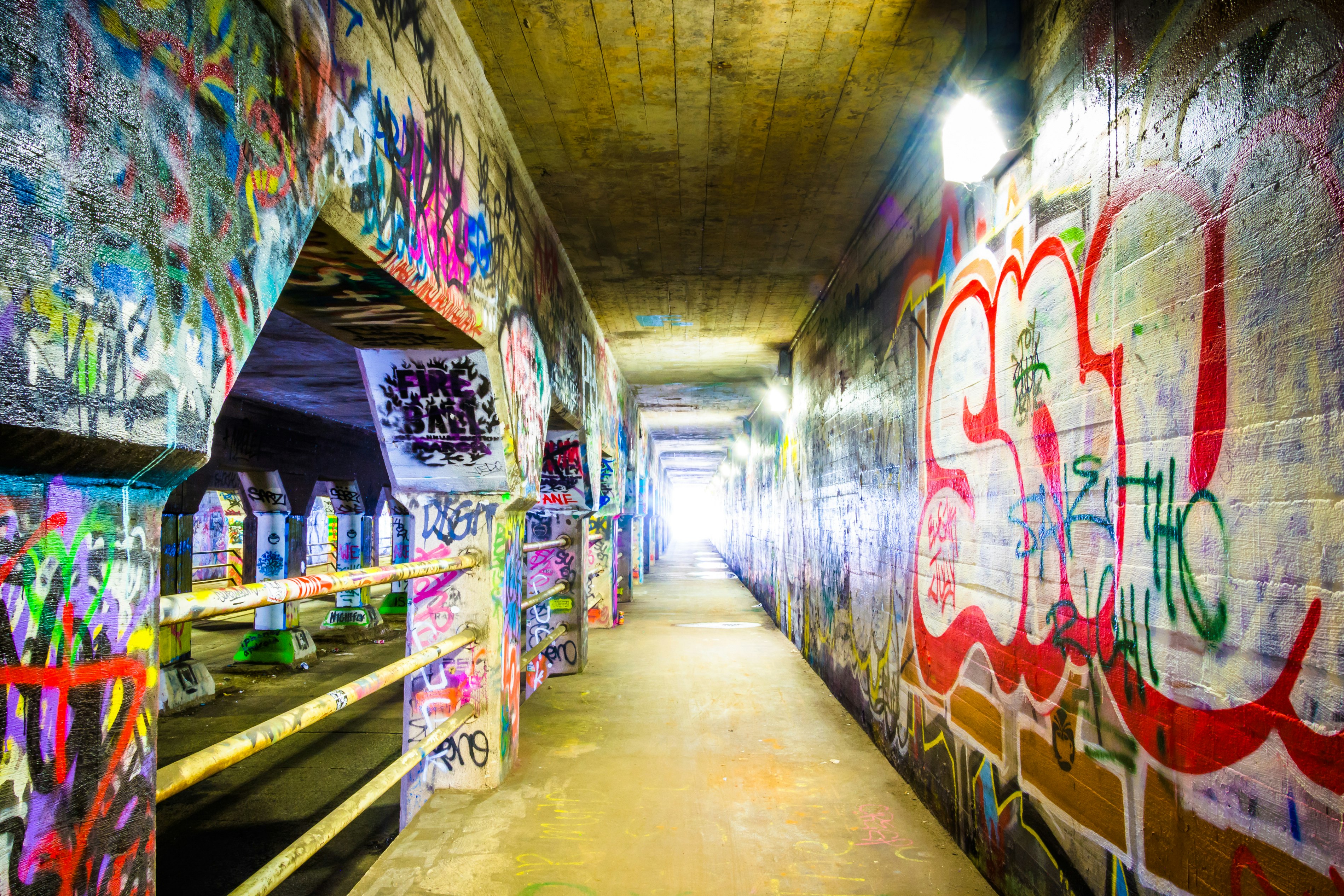 A colorfully graffitied tunnel, covered from top to toe in script