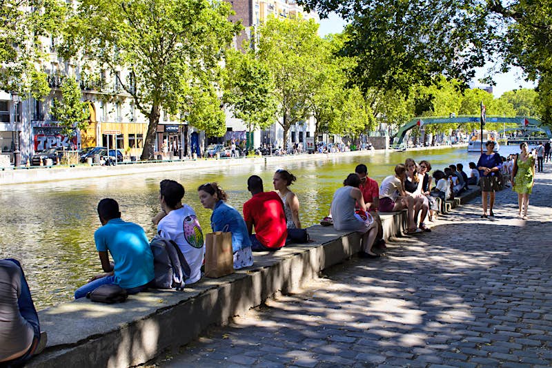 Canal_St_Martin_Paris_Lonely_Planet.jpg Groups of people sit on the small wall that runs along the banks of Canal St-Martin, a canal in central Paris on a sunny day.