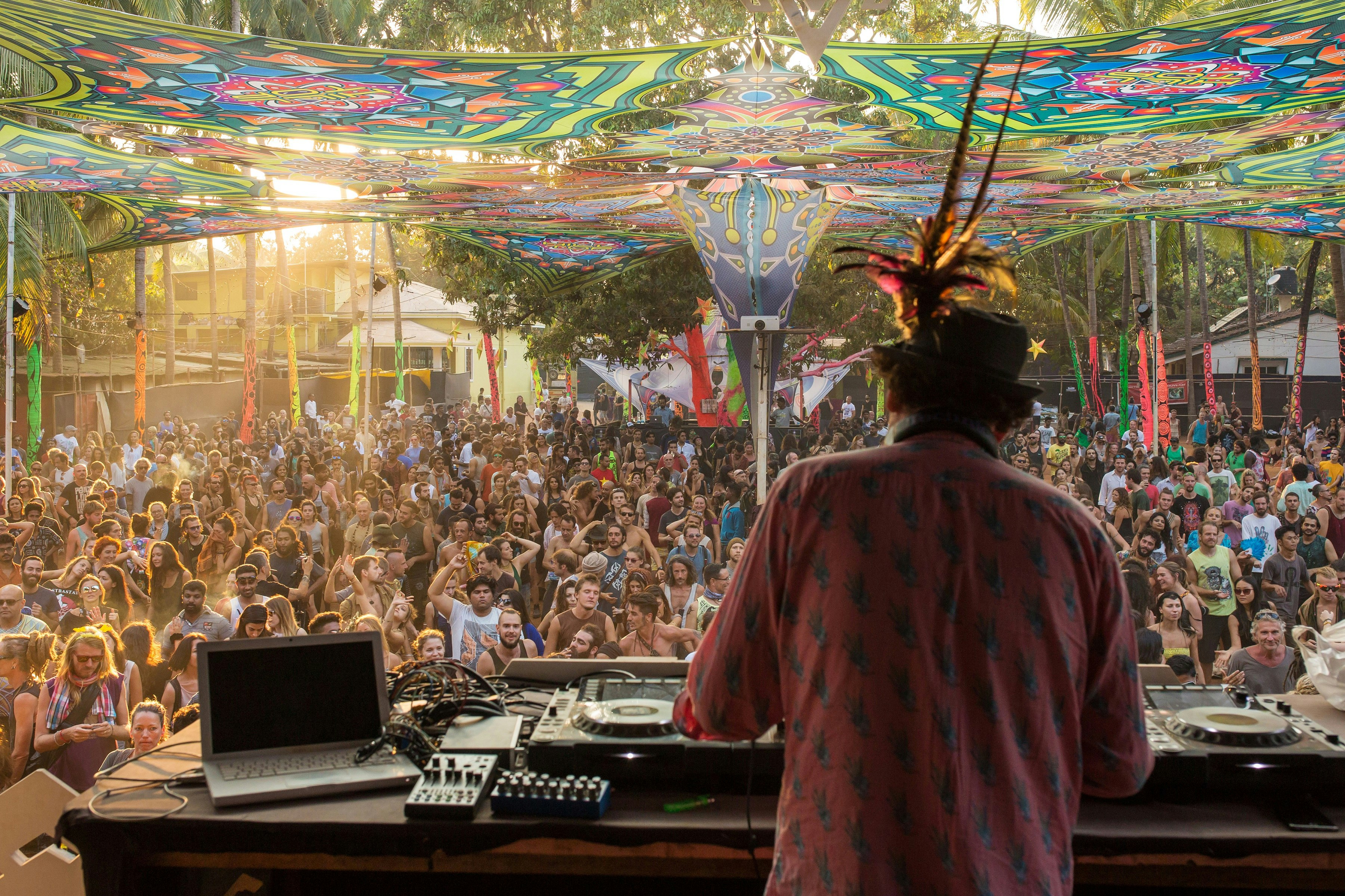 A DJ, on a raised stage, spins the decks in front of a large crowd at HillTribe club in Goa.