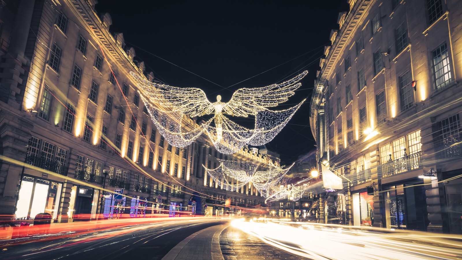 Long exposure shot of the angel-shaped Christmas lights on Regent Street, London. There are blurred lights from cars on the road. 