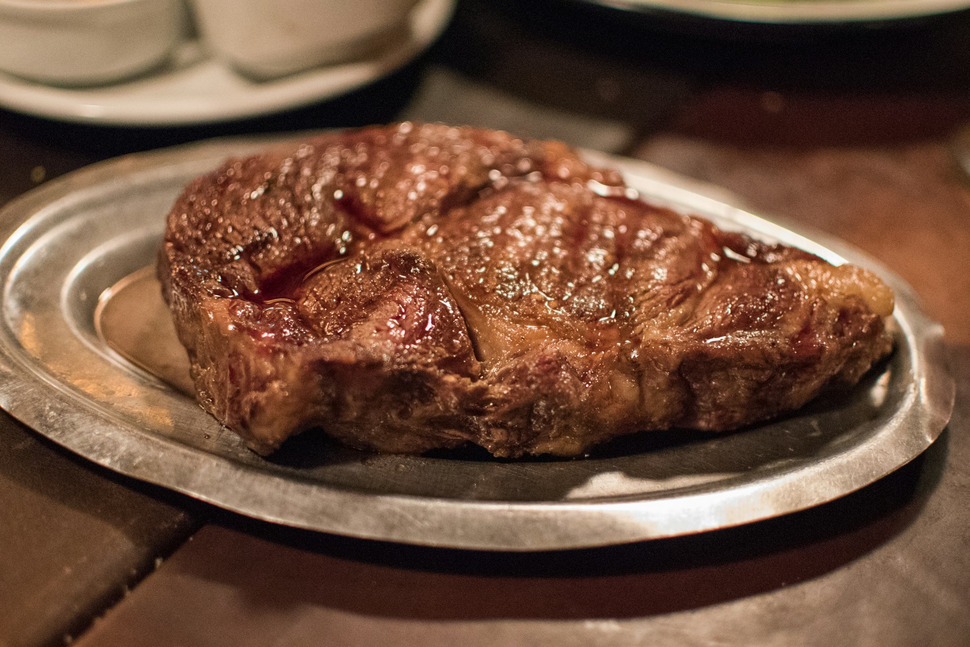Closeup of a large cut of juicy steak on a silver platter 