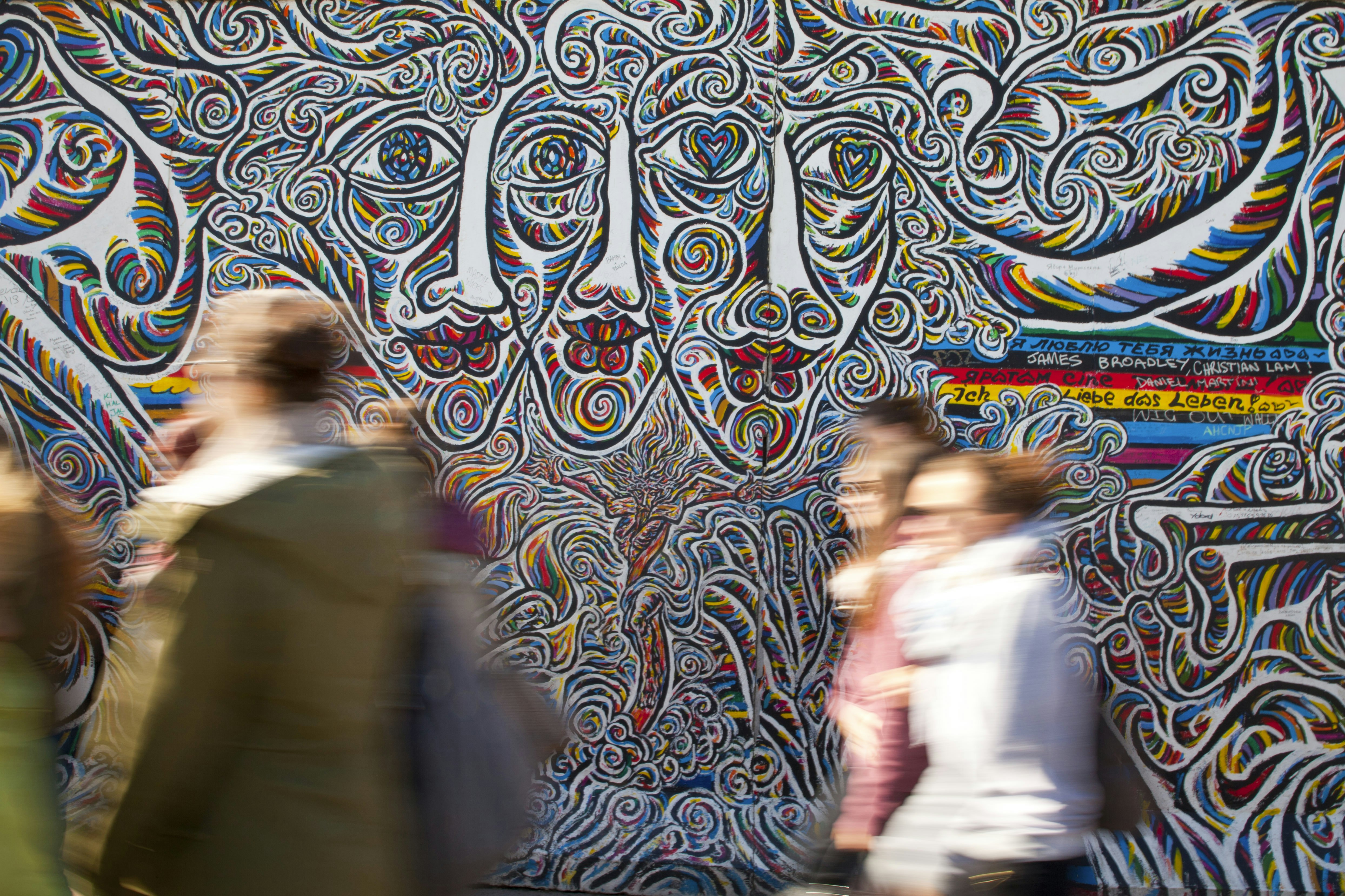 People walk past a colorful mural in Germany's capital