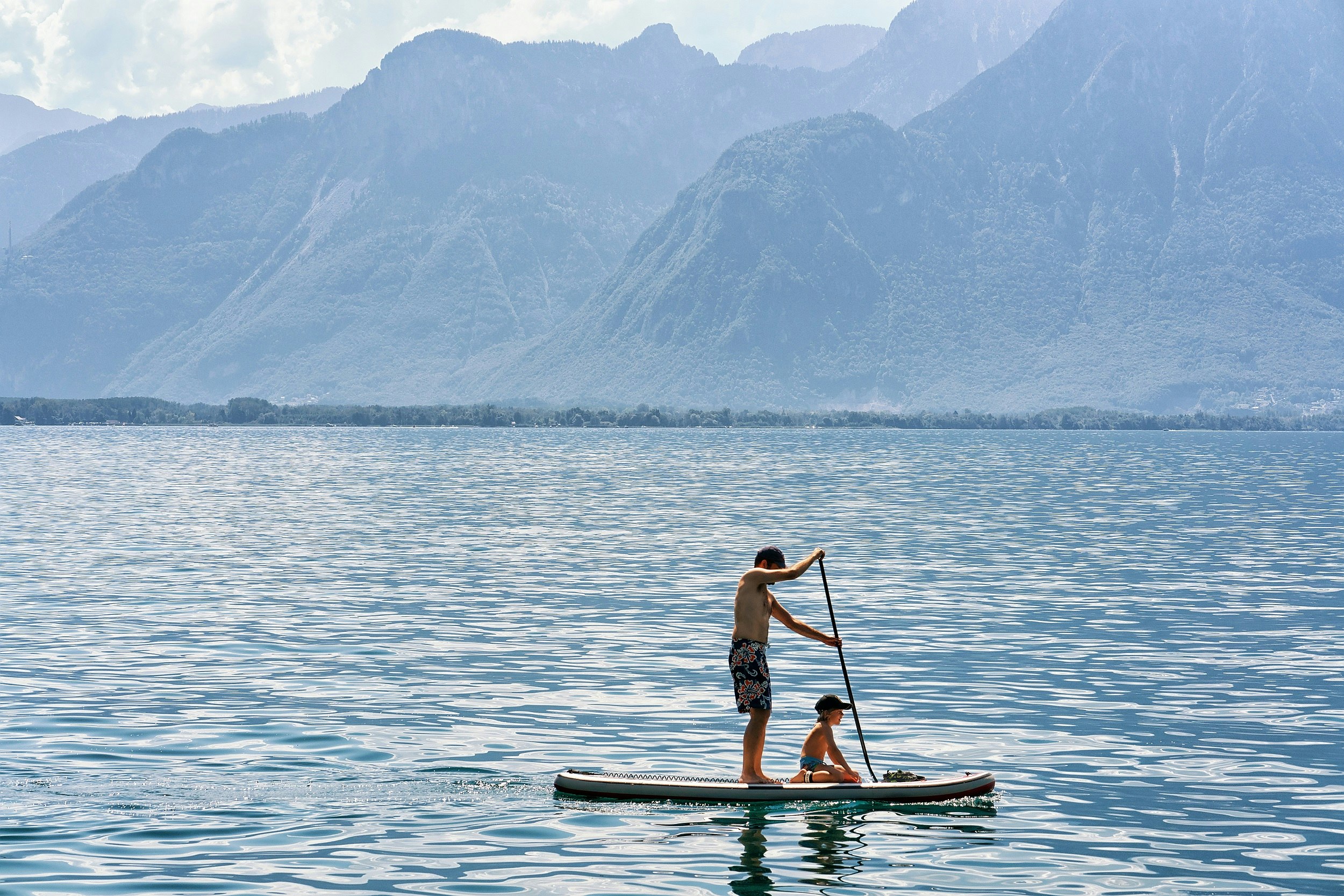Man and a boy on a standup paddle board on Geneva Lake in Montreux.