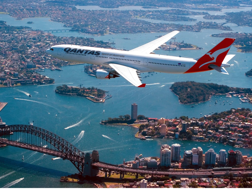 Aerial shot of Sydney with a Qantas dreamliner in the sky