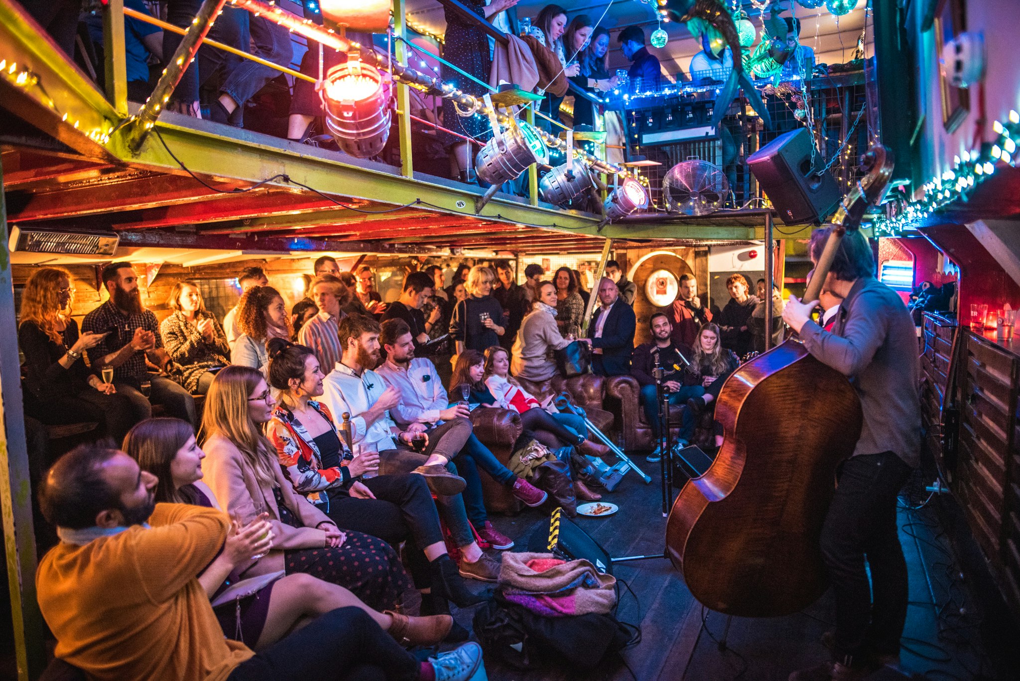 Inside the Tamesis barge, an intimate gig is in progress; the double-bass player in the foreground is obscuring the rest of the band.