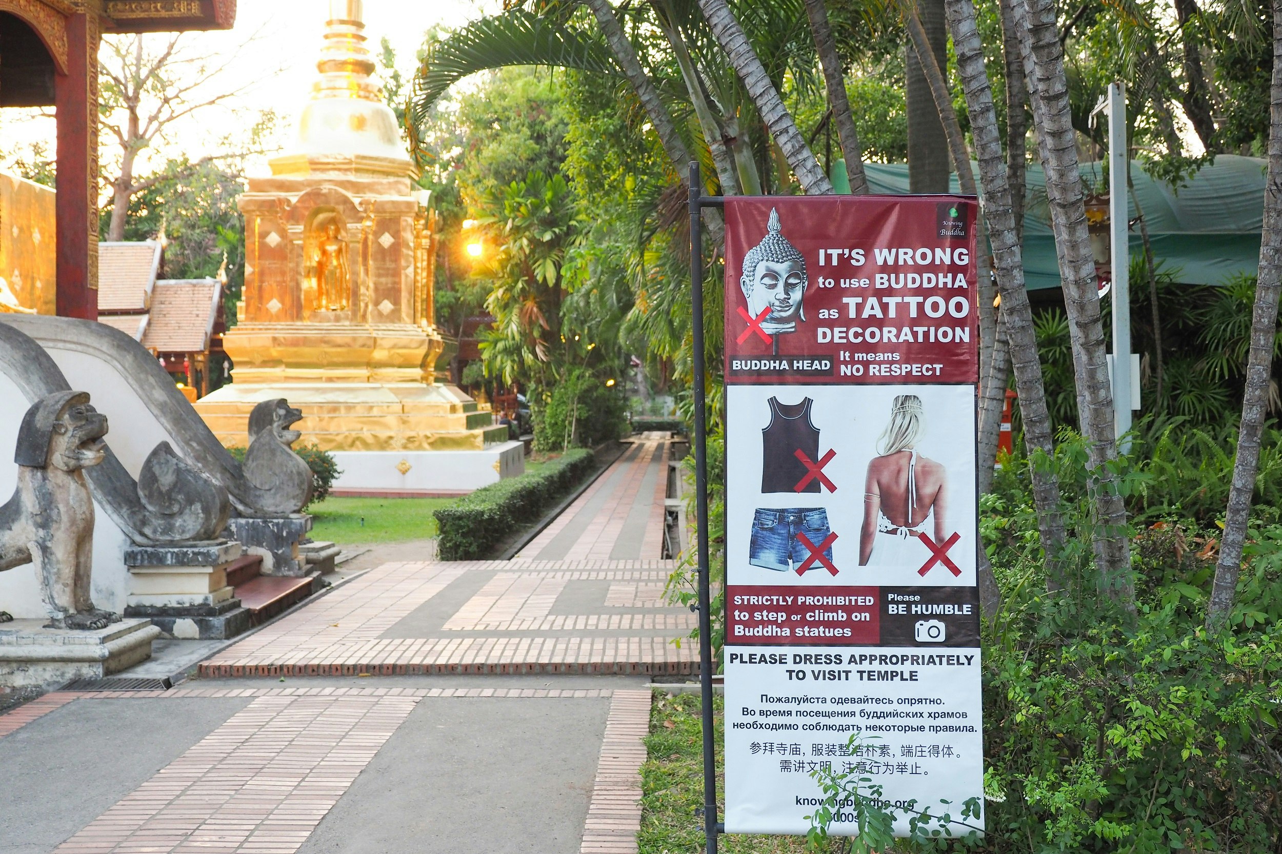 A poster near the entrance to temple grounds states "It's wrong to use Buddha as tattoo decoration". It has pictures of inappropriate dress (shorts and vests) with large red crosses next to them.