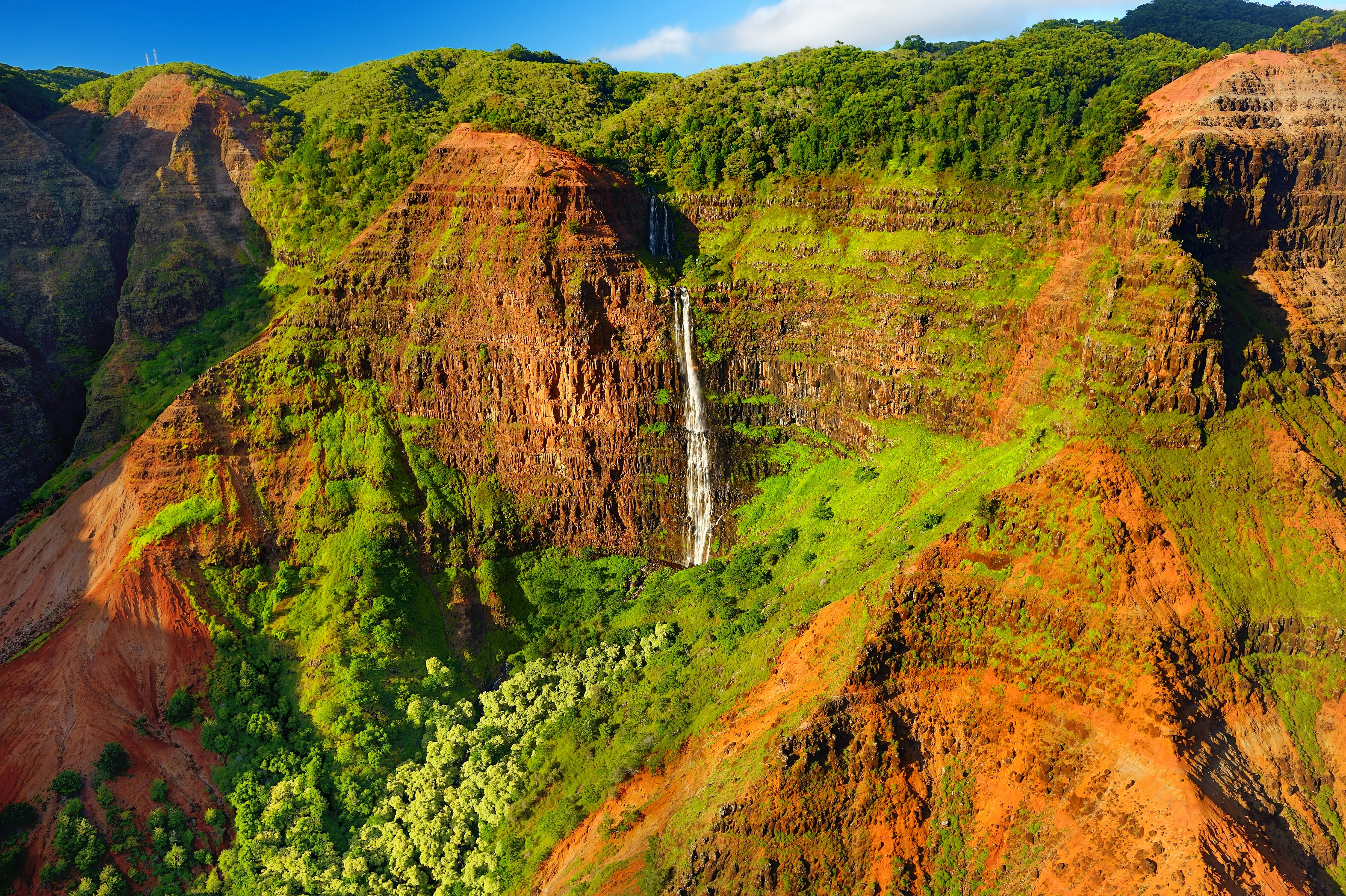 A waterfall cascades down the lush cliffs of Waimea Canyon State Park in Kauai.jpg