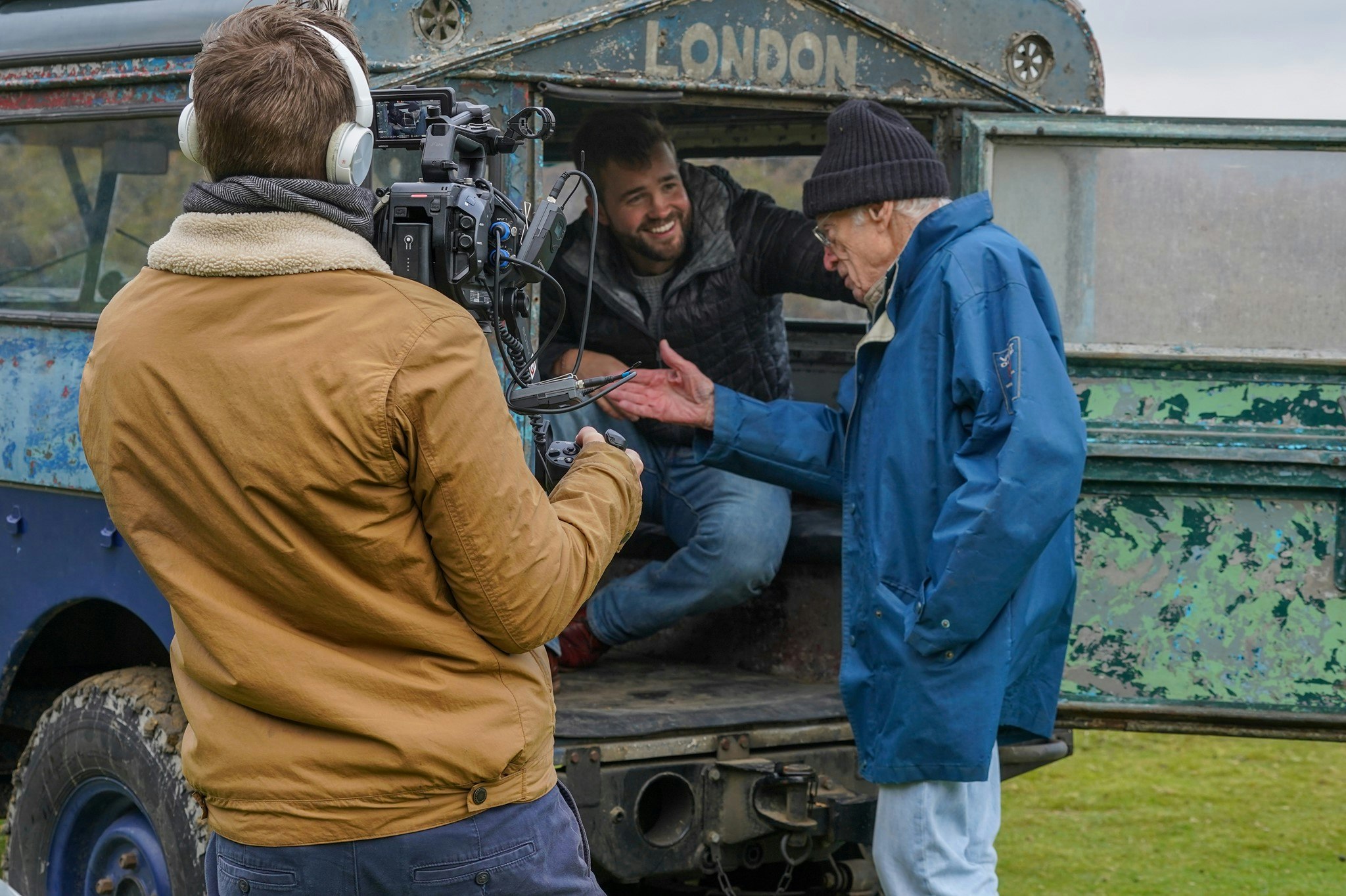 Tim Slessor (87) and two cameramen stand by a Land Rover vehicle