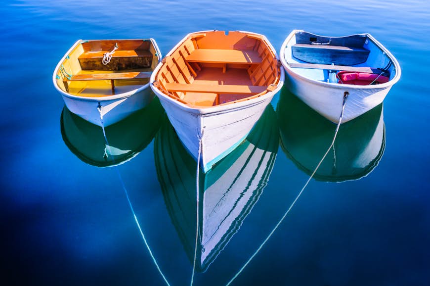 Three rowboats float gently on the quiet waters od Quissett Harboe in Falmouth, Massachusetts, on a Autumn afternoon.