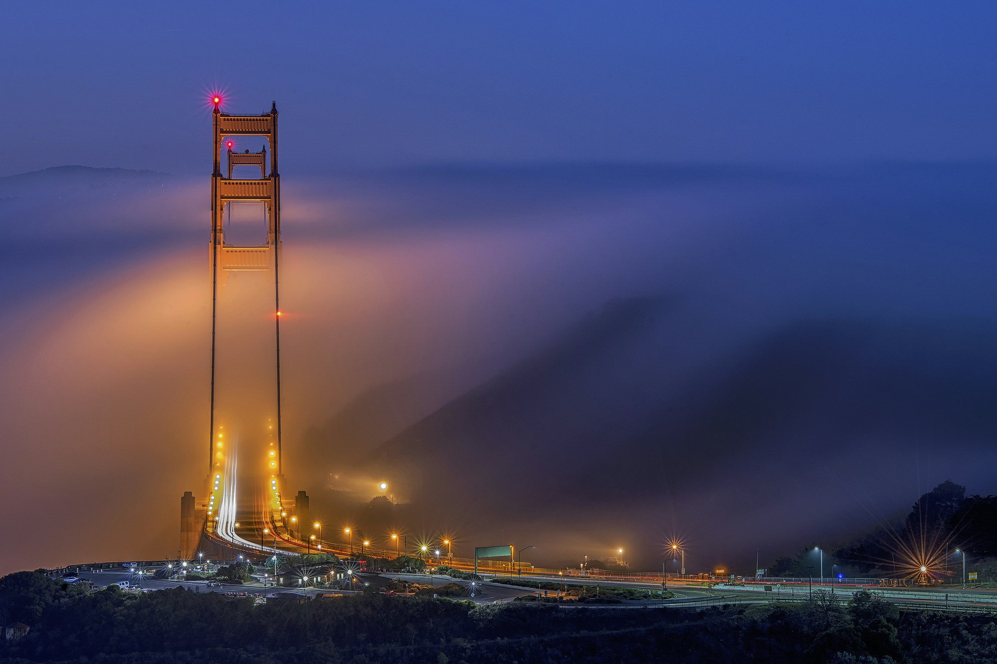 A picture of San Francisco's Golden Gate bridge emerging from the fog at sunset
