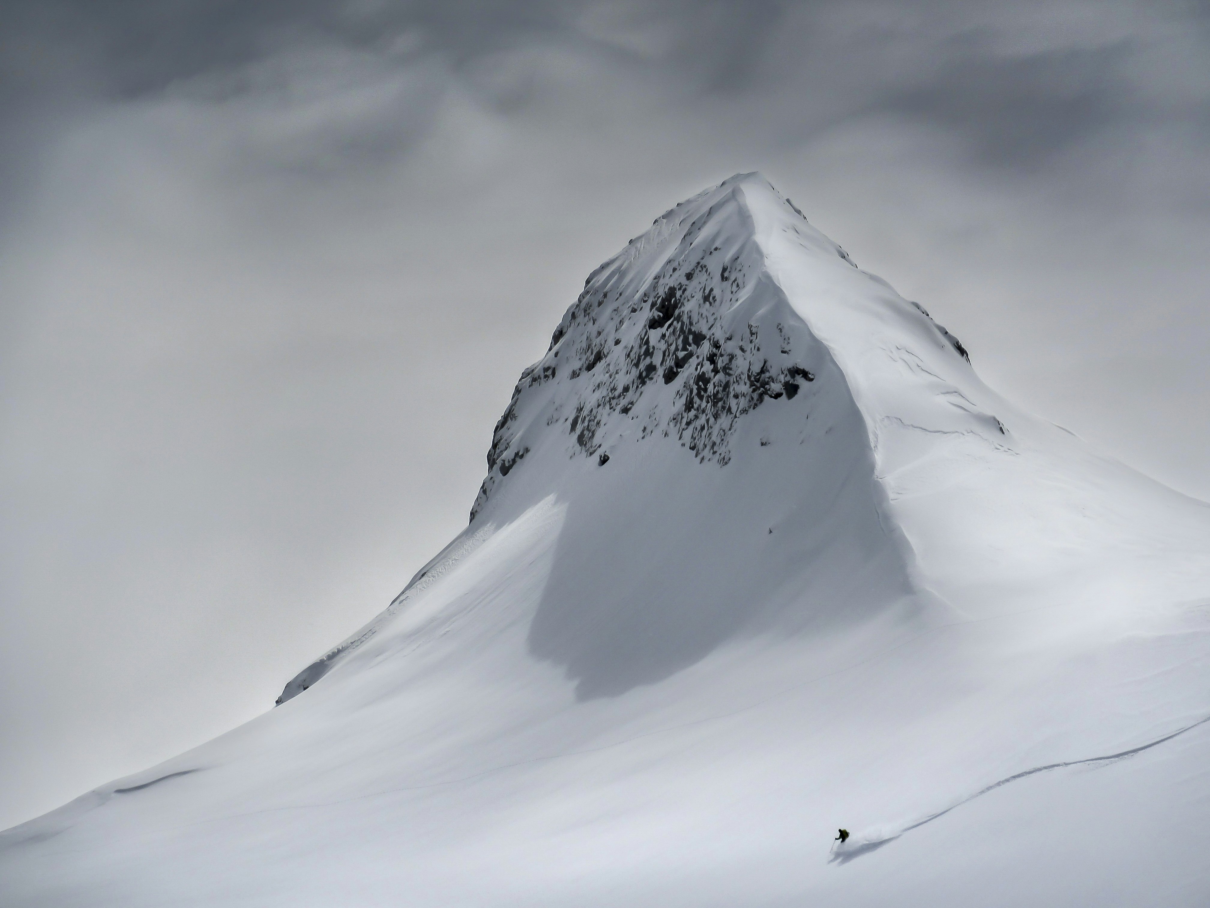 A picture of a lone skier speeding down the slope of a Slovenian alpine peak
