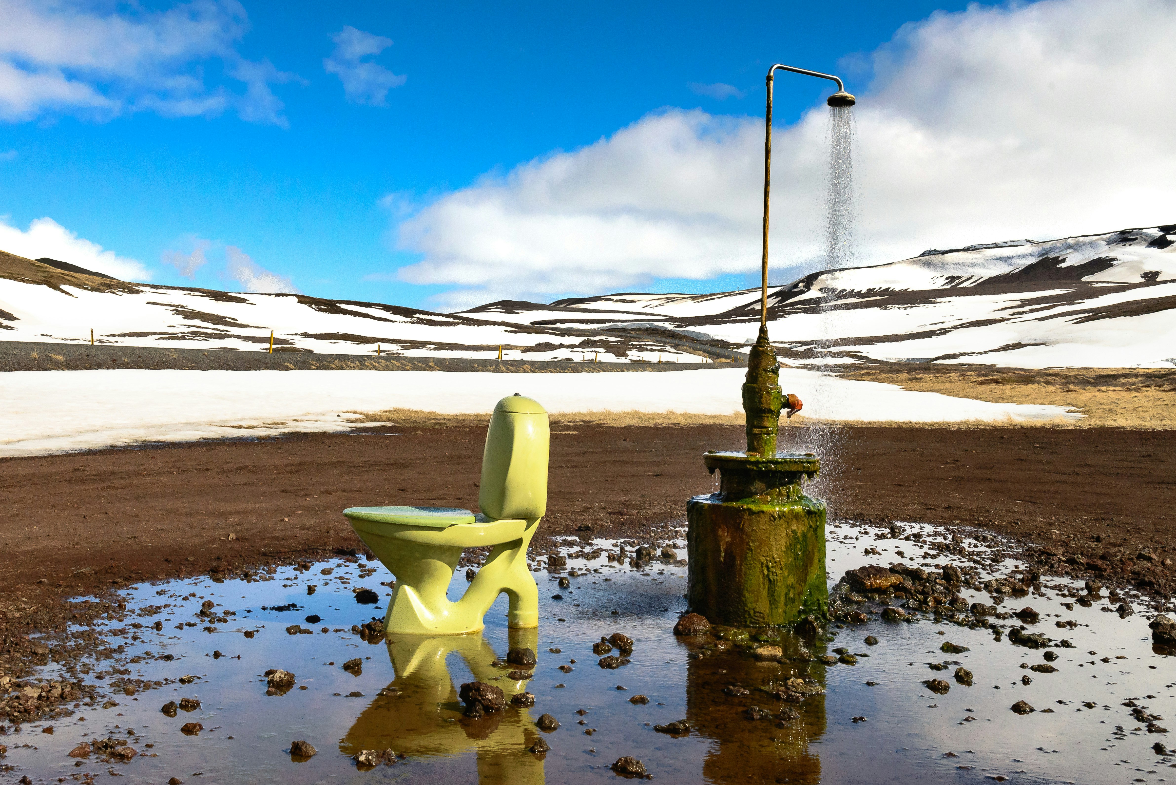 A toilet and shower stand in the middle of a wide dirt plain