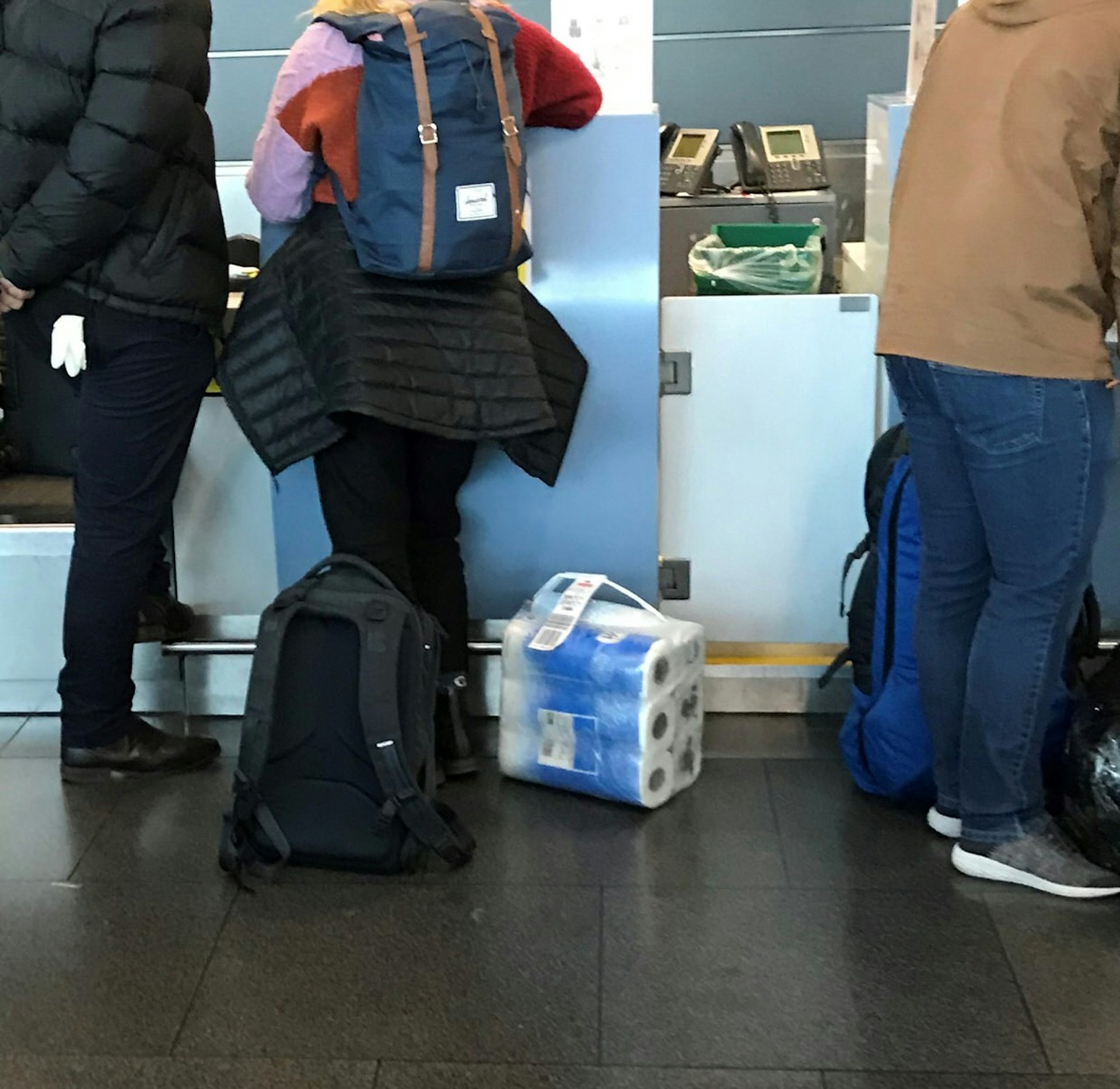 A person checking in for a flight with a packet of toilet paper as their carry on