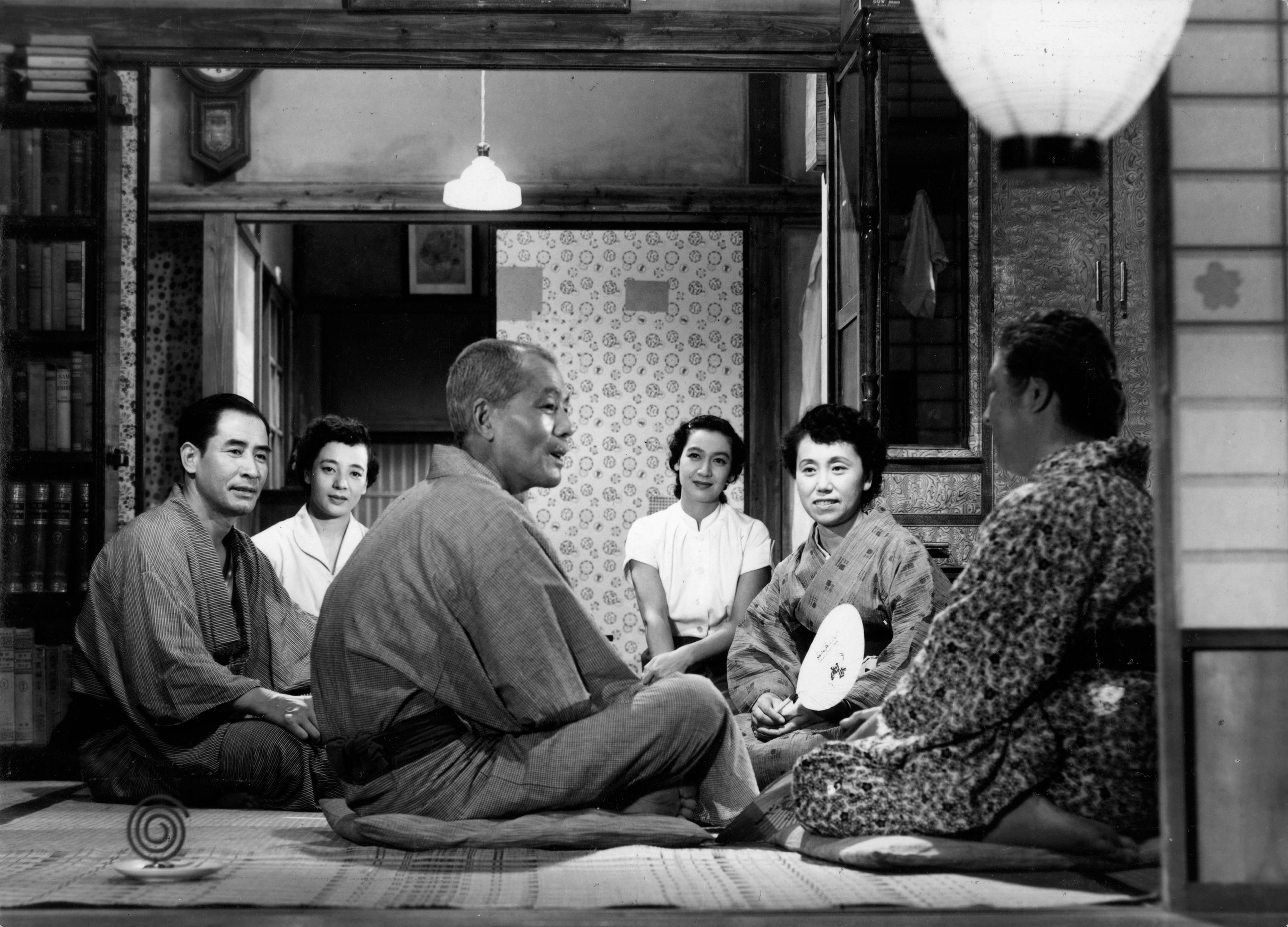 A family are sitting cross-legged on the floor in a house in a scene from 'Tokyo Story' (1953).