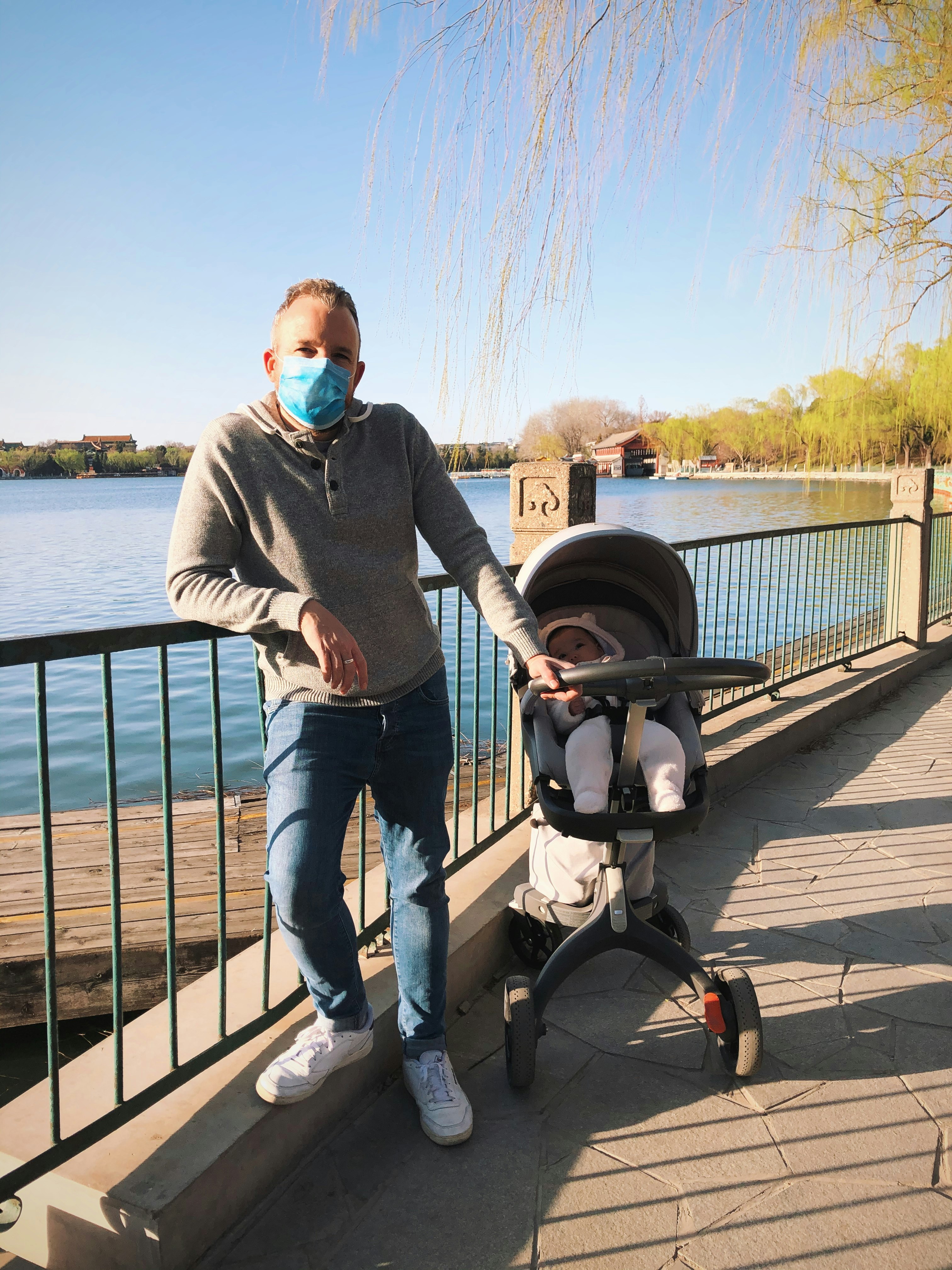 Tom O'Malley wearing a face mask in a park in Beijing with a pram next to him