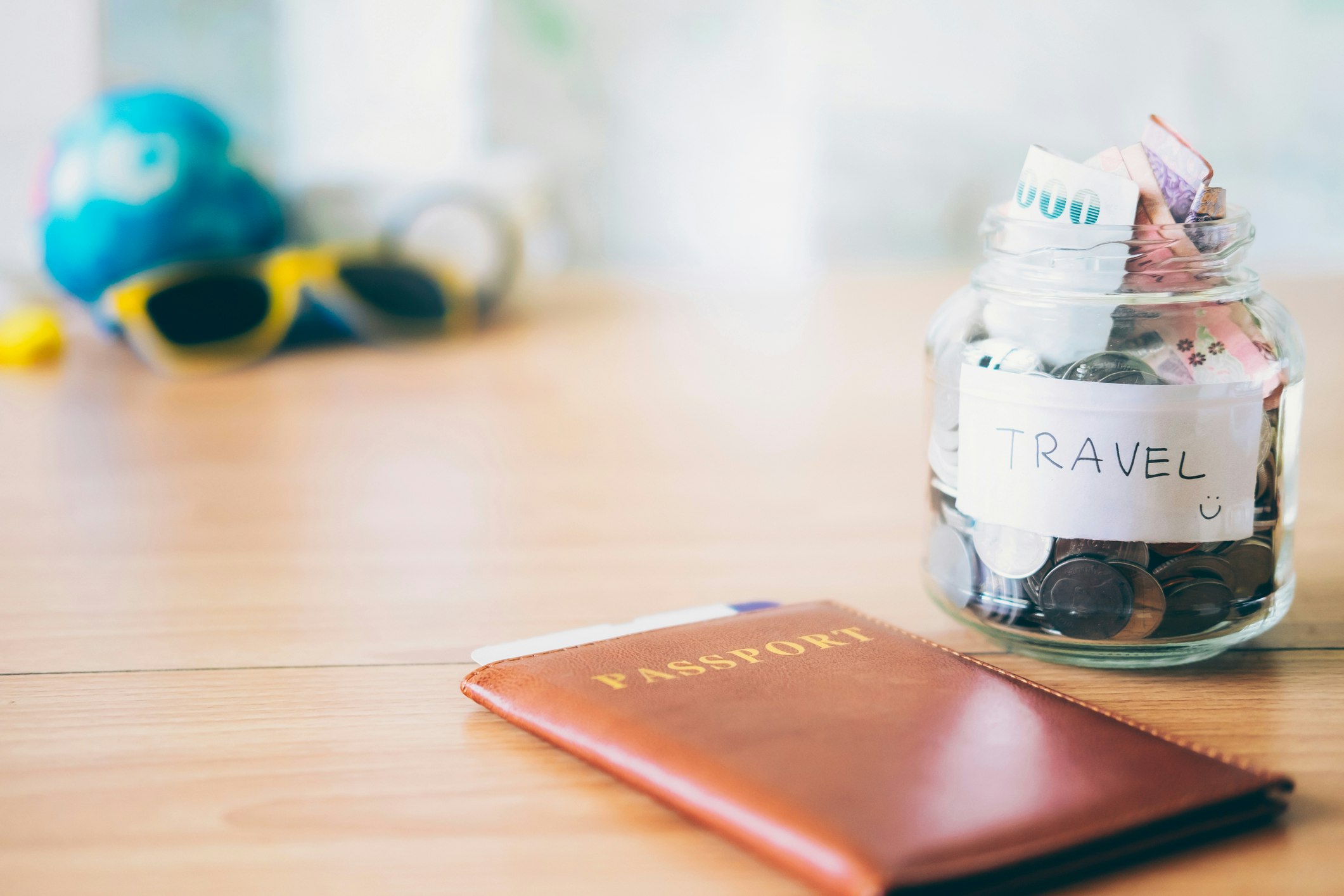 A picture of a passport and a jar of bills labeled as "travel" with a smiley face