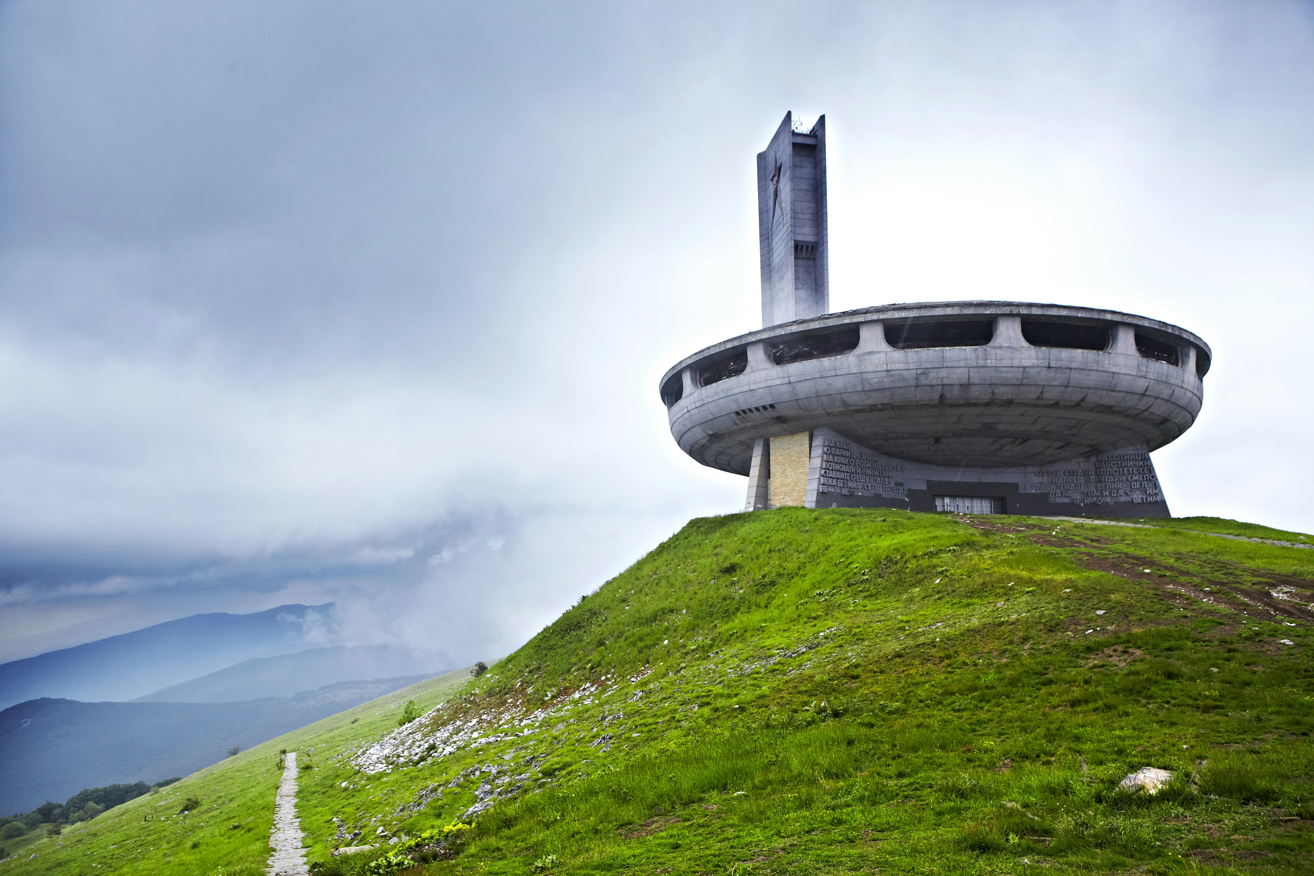 Looking much like an alien flying saucer, the concrete disc of the Buzludzha Monument stands on a grassy hill.