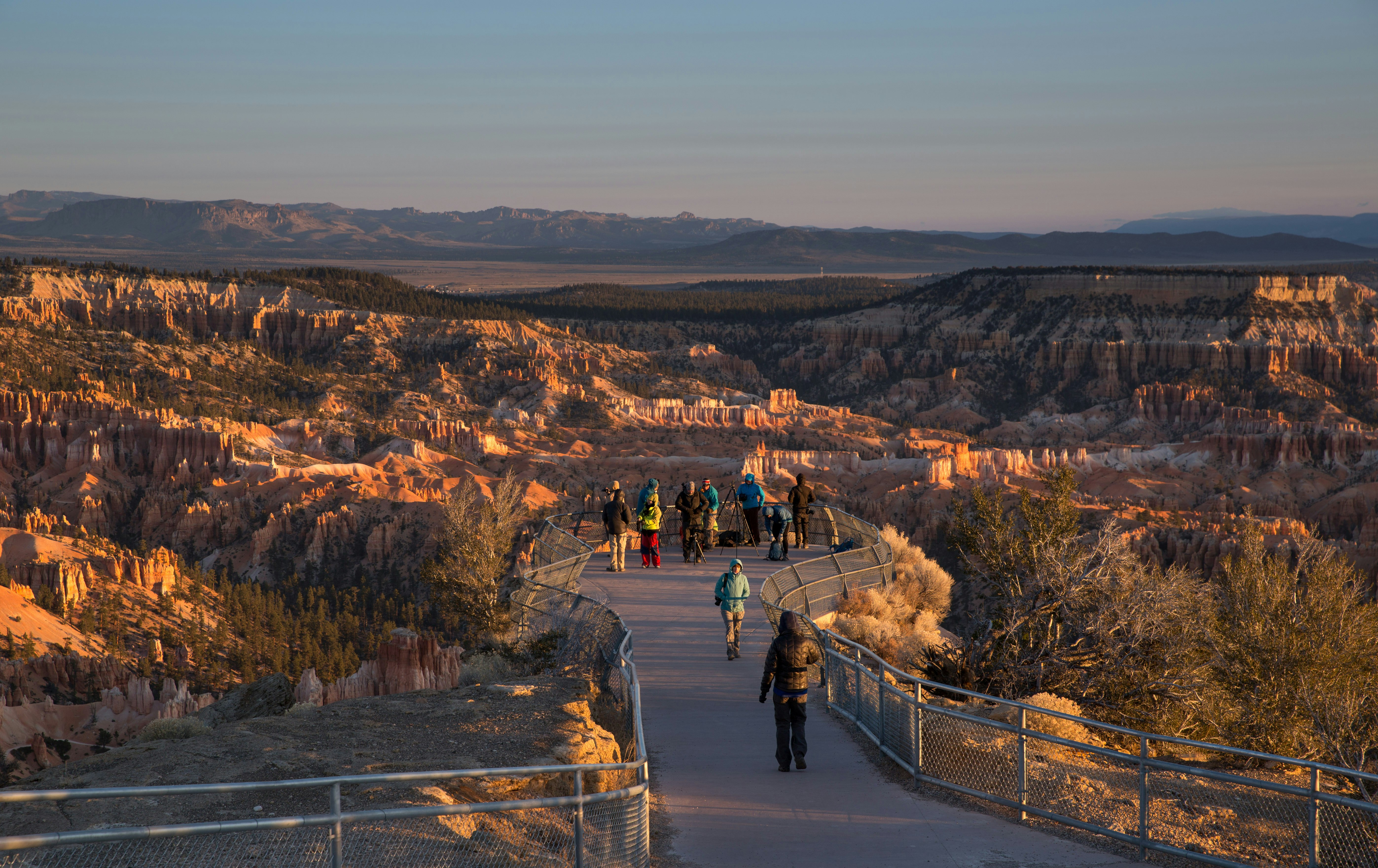 Tourists line up to take pictures of Bryce Canyon National Park at an overlook near painted desert plateaus and other rock formations