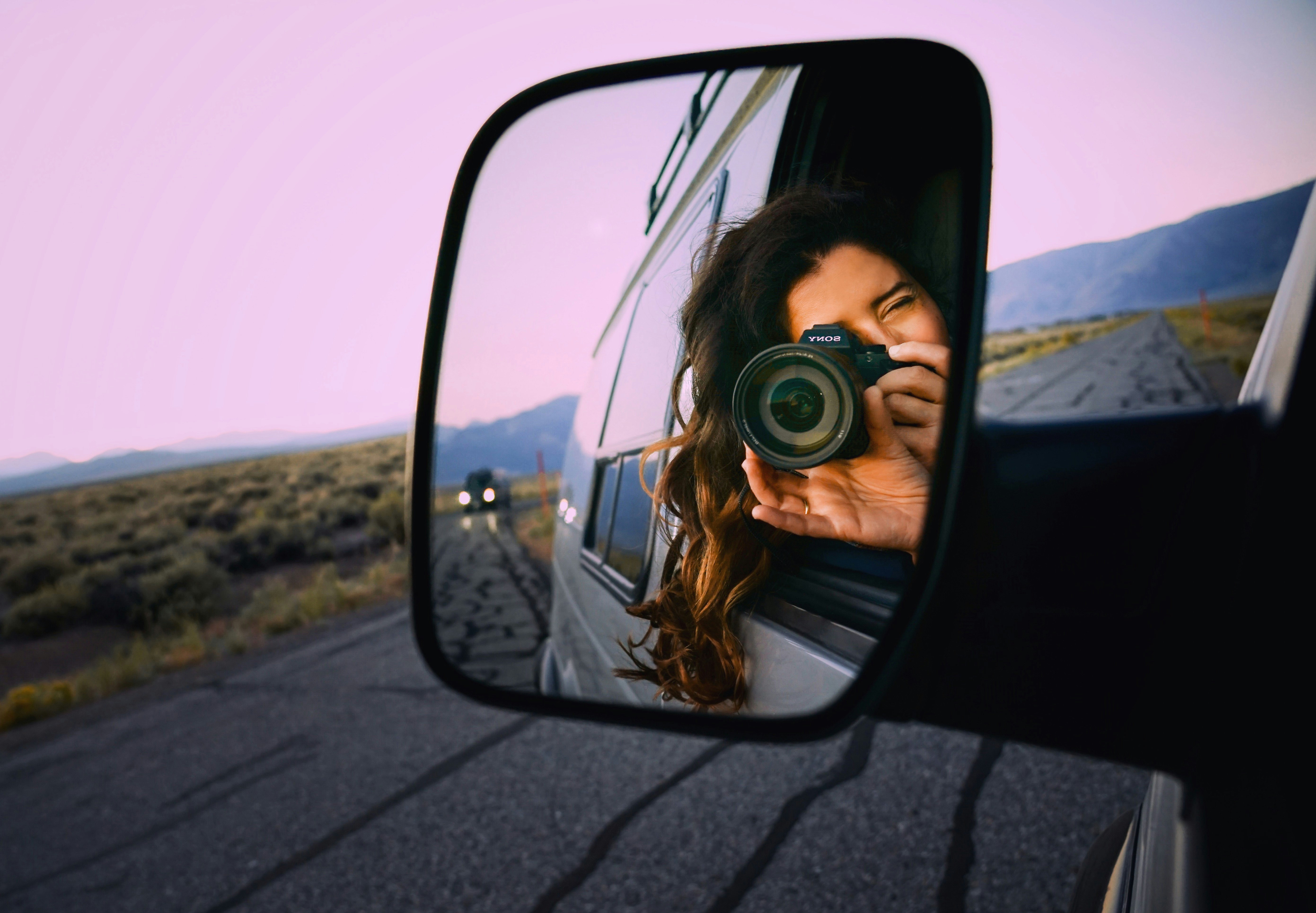 a woman with a camera reflected in a van mirror