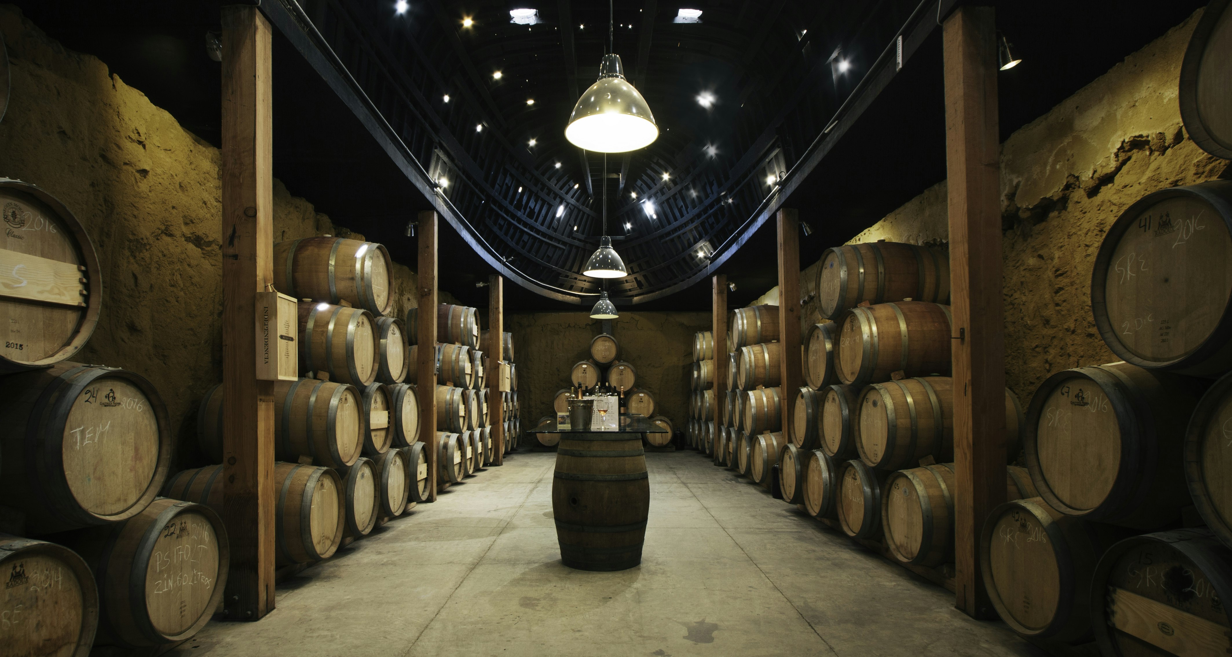 Wooden wine barrels line the walls of a dark cave