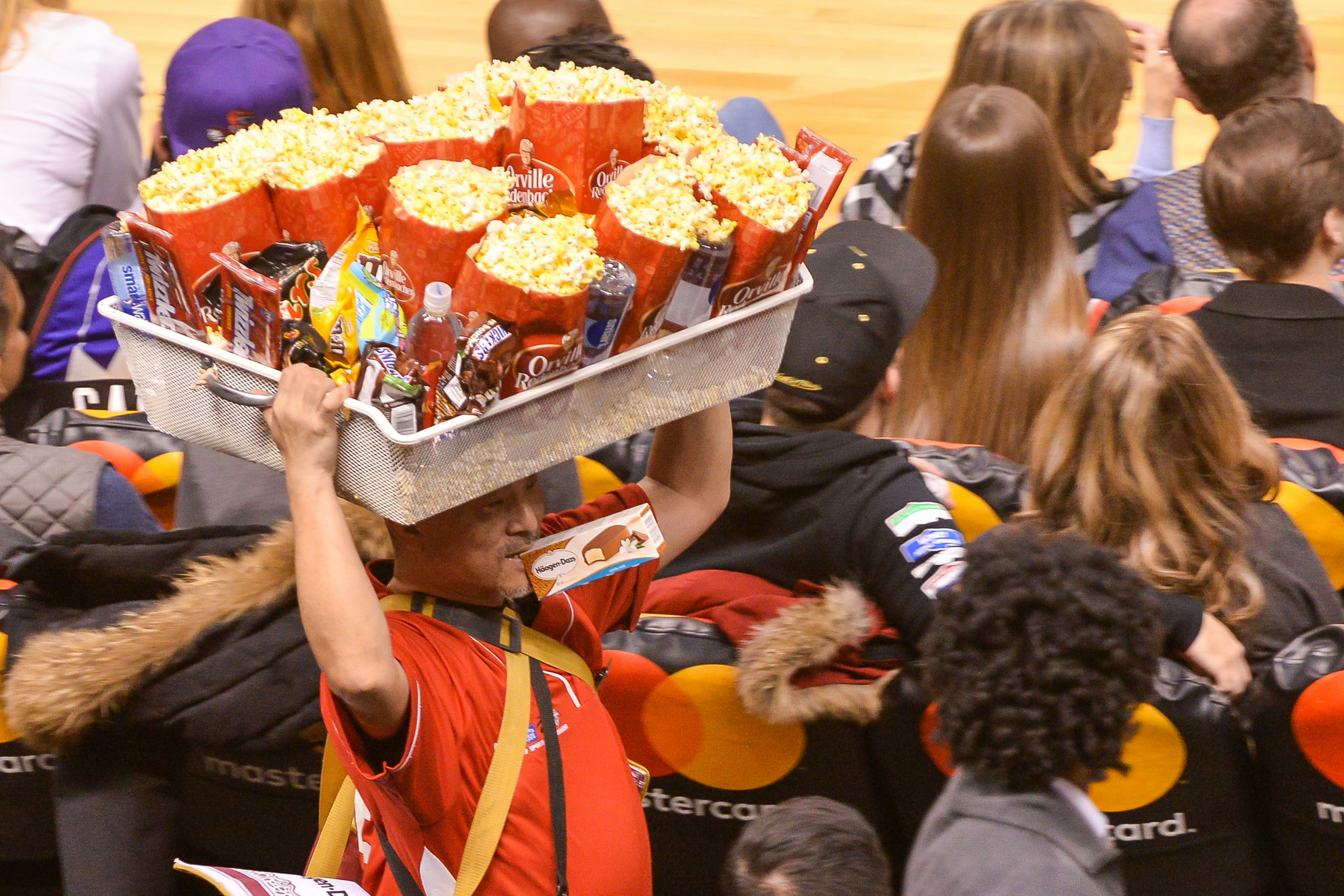 vendor carrying tub full of popcorn and candy on his head at an NBA game
