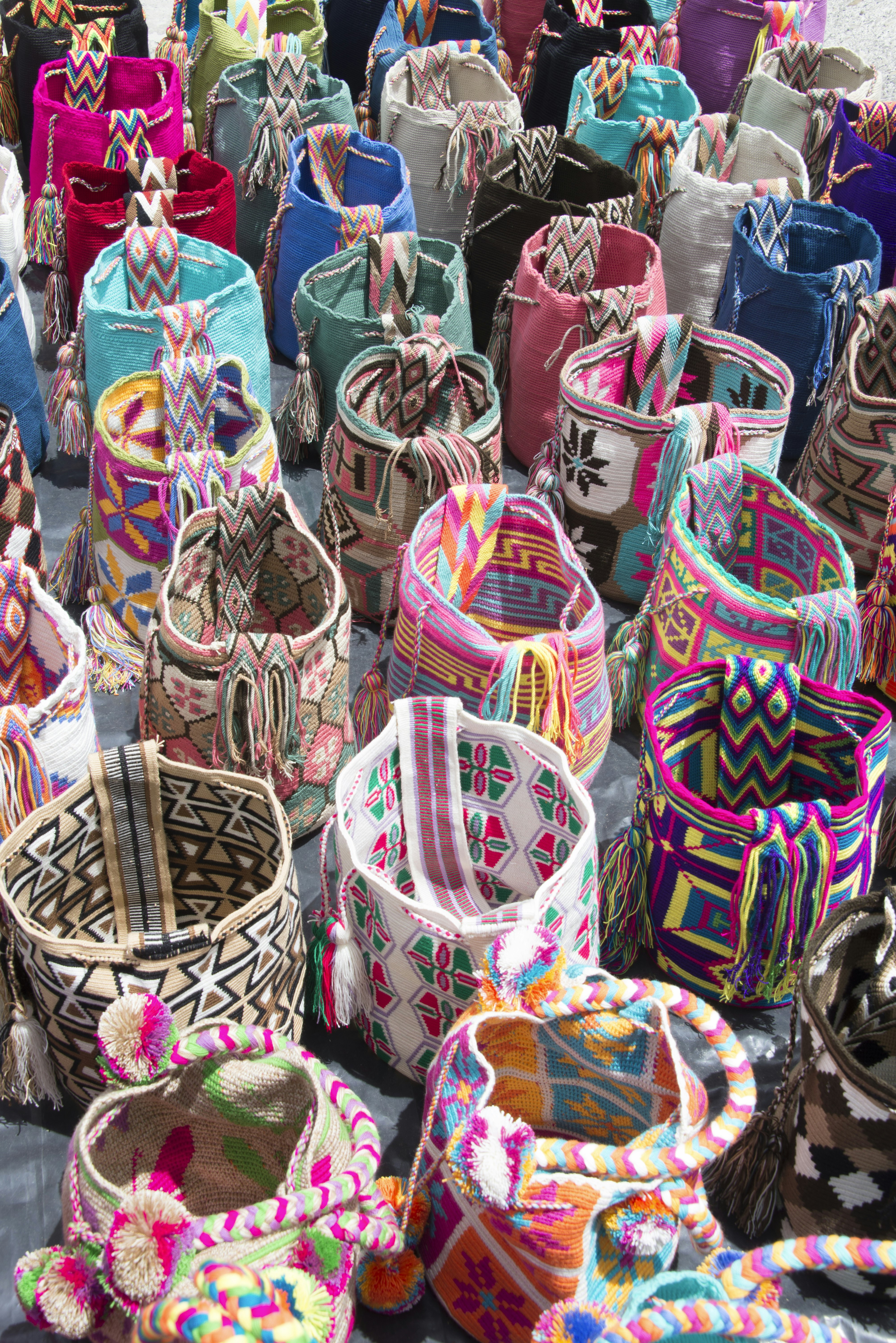 A display of many brightly colored bags, woven by the Wayúu indigenous people; each bag has its own unique geometric pattern.