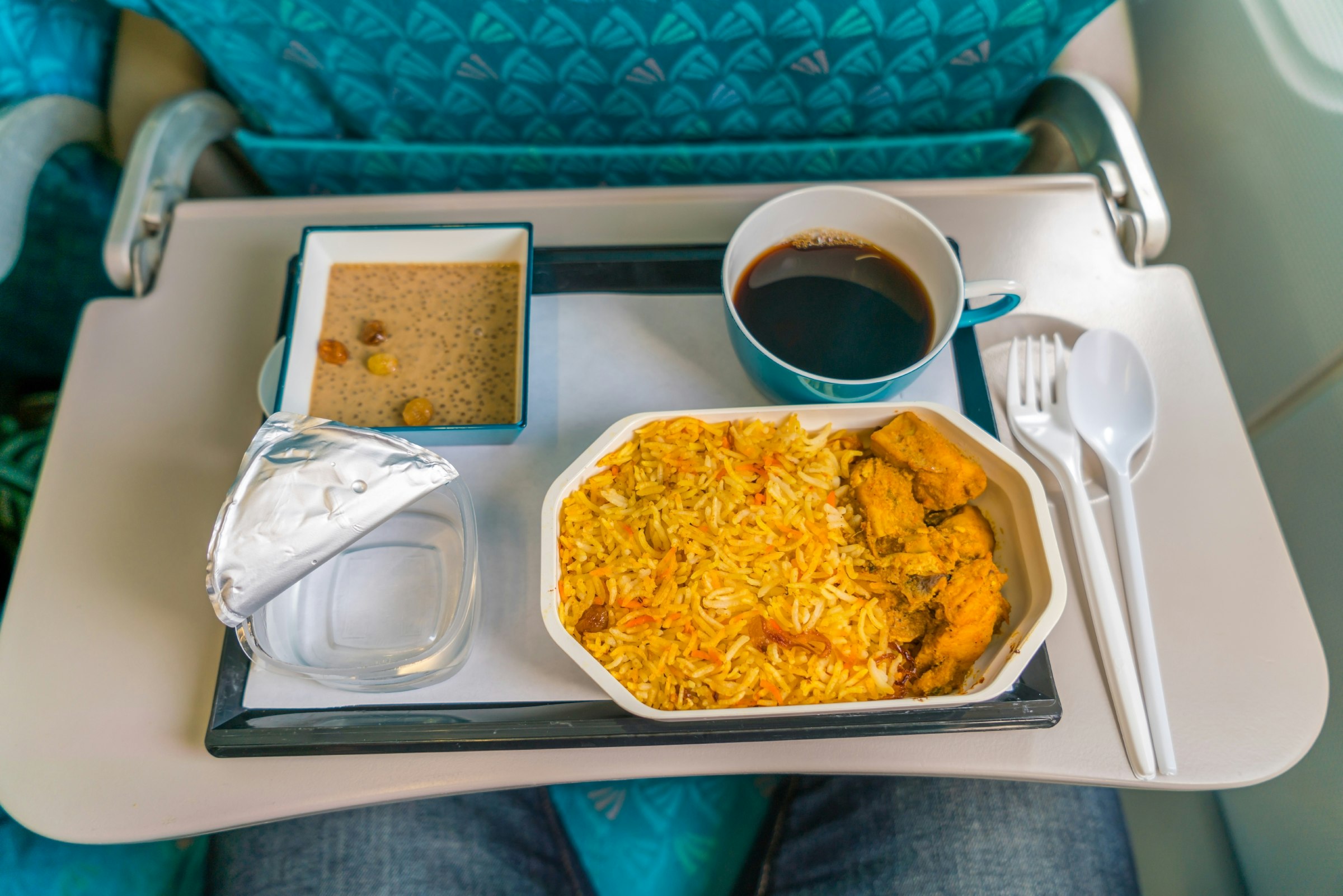A curry and coffee on a tray on an airplane