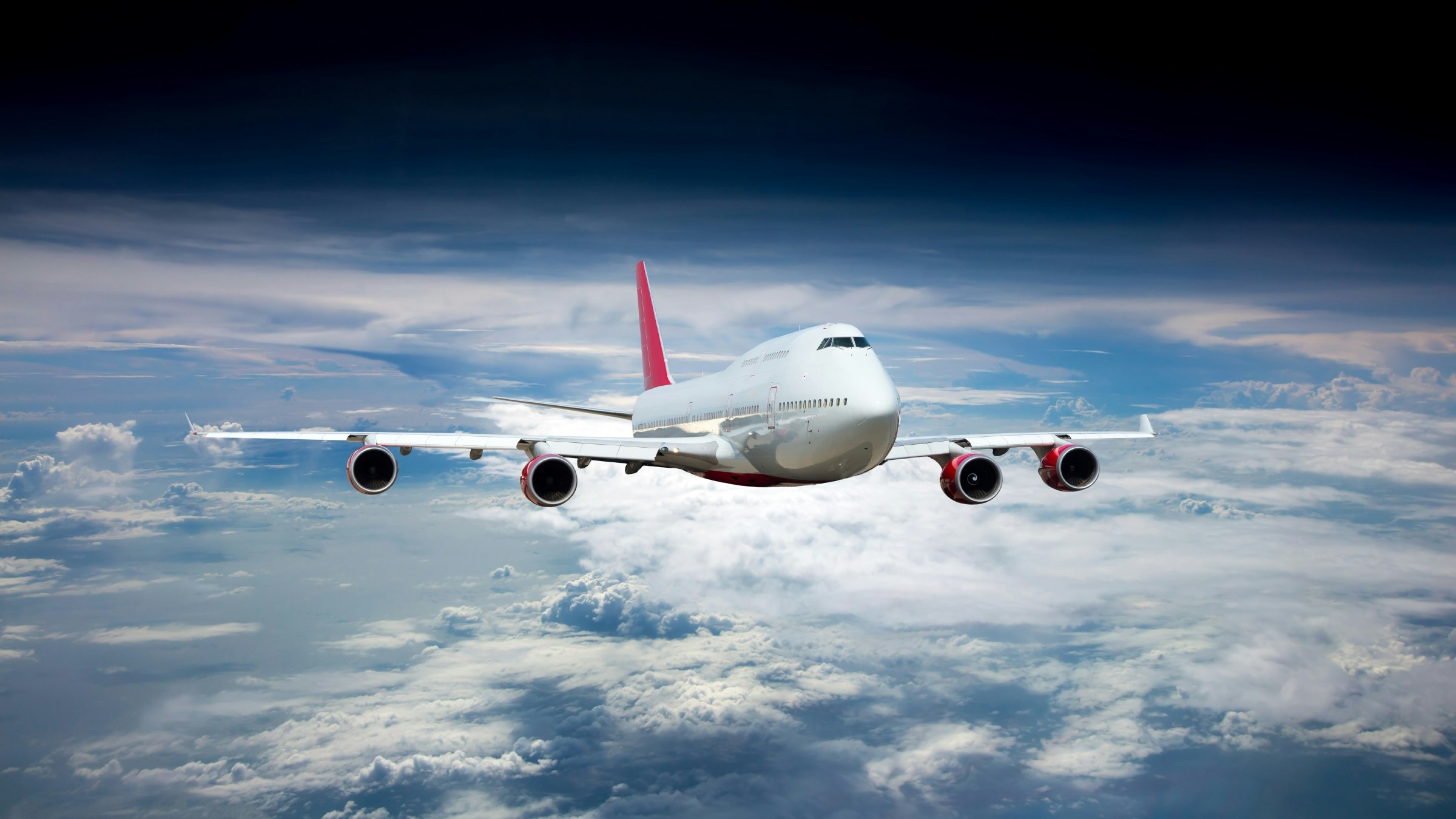 White passenger jet plane flying above the clouds. 