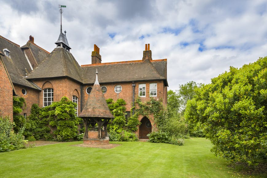 Красный дом Уильяма Морриса;  просторный дом из красного кирпича в готическом стиле с башенками, окруженный пышным ландшафтным садом
