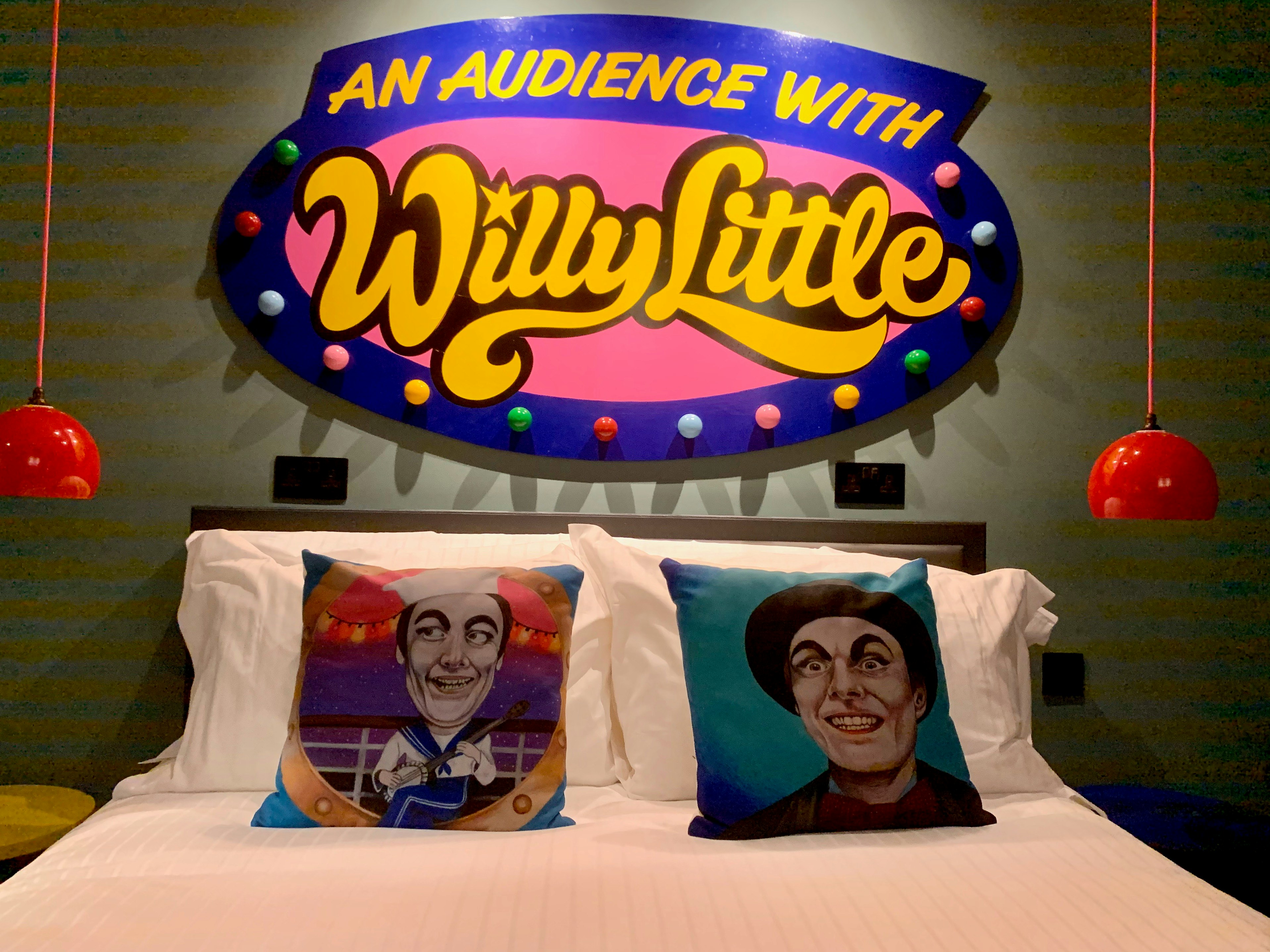 A garish sign hangs above a bed saying 'An audience with Willie Little', in the brightly coloured Willie Little Ocean Suite at Art B&B, Blackpool.