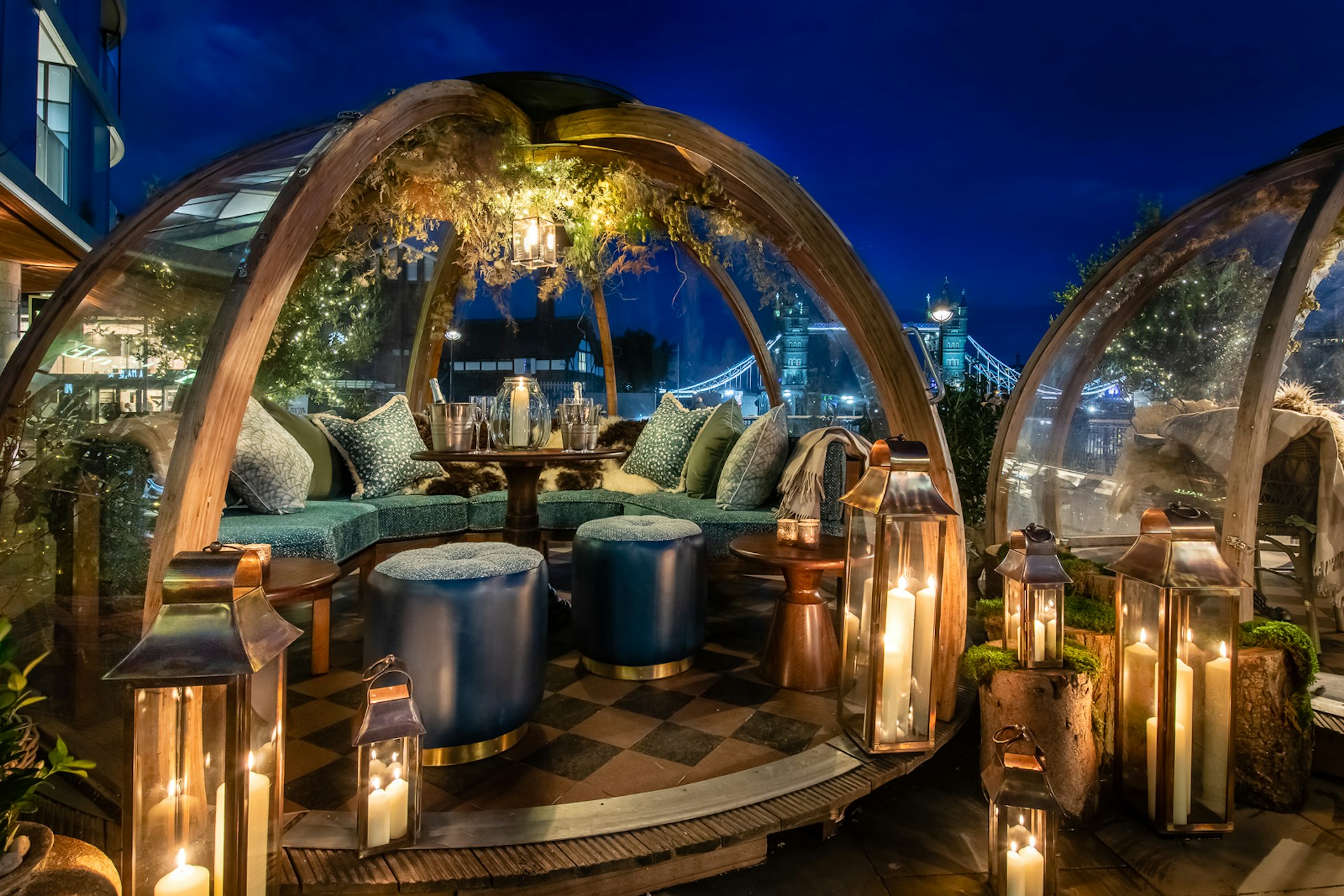 Stylish transparent igloos at Coppa Club in London are decorated with plush soft furnishings, large church candles inside glass lanterns and festive garlands.