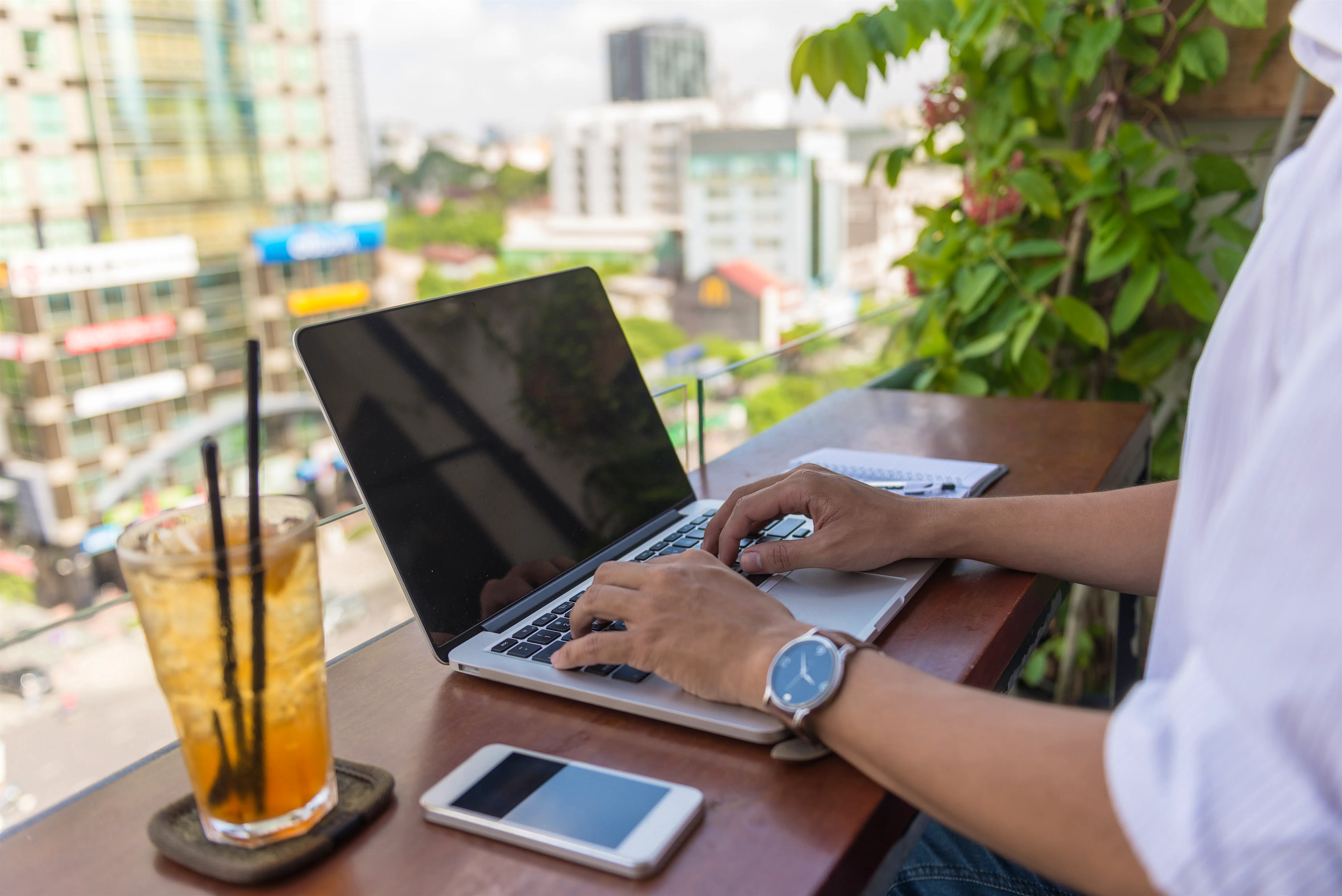 man typing.jpg A man types on a laptop on a balcony
