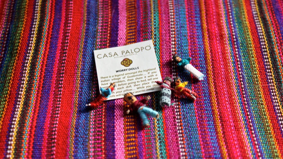 Small, finger-sized 'worry dolls' have been placed on a blanket next to a note. 