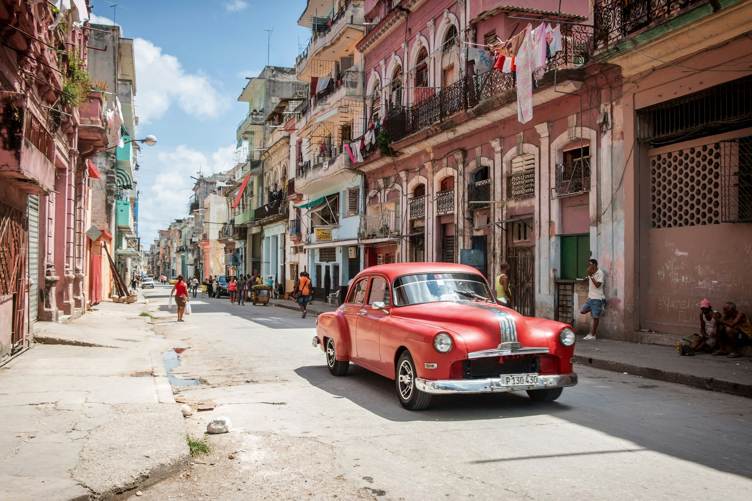 A classic American car is parked in a colorful street in Havana.