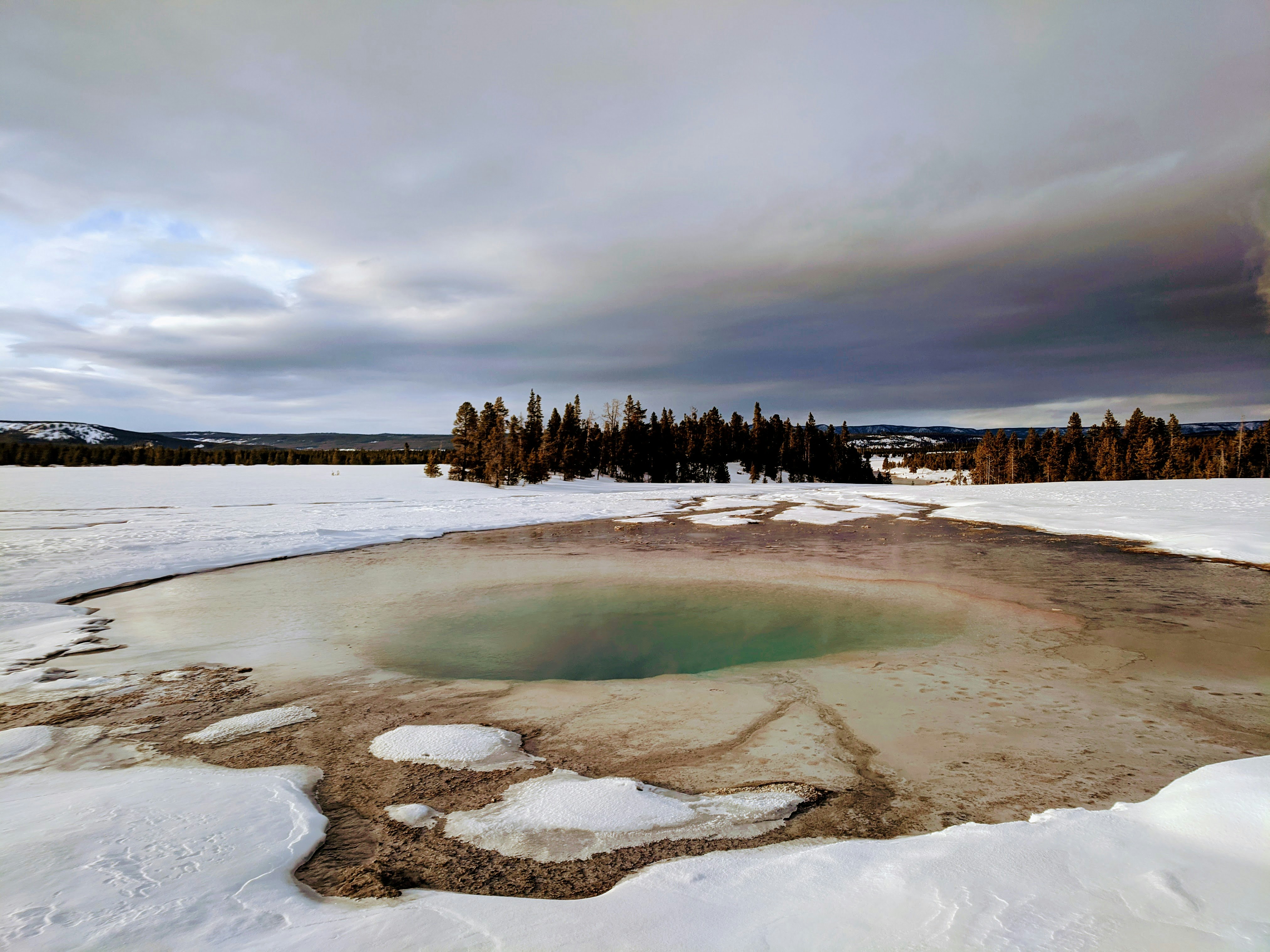 Turquoise Pool in Yellowstone National Park surrounded by a contrasting blanket of fresh white snow