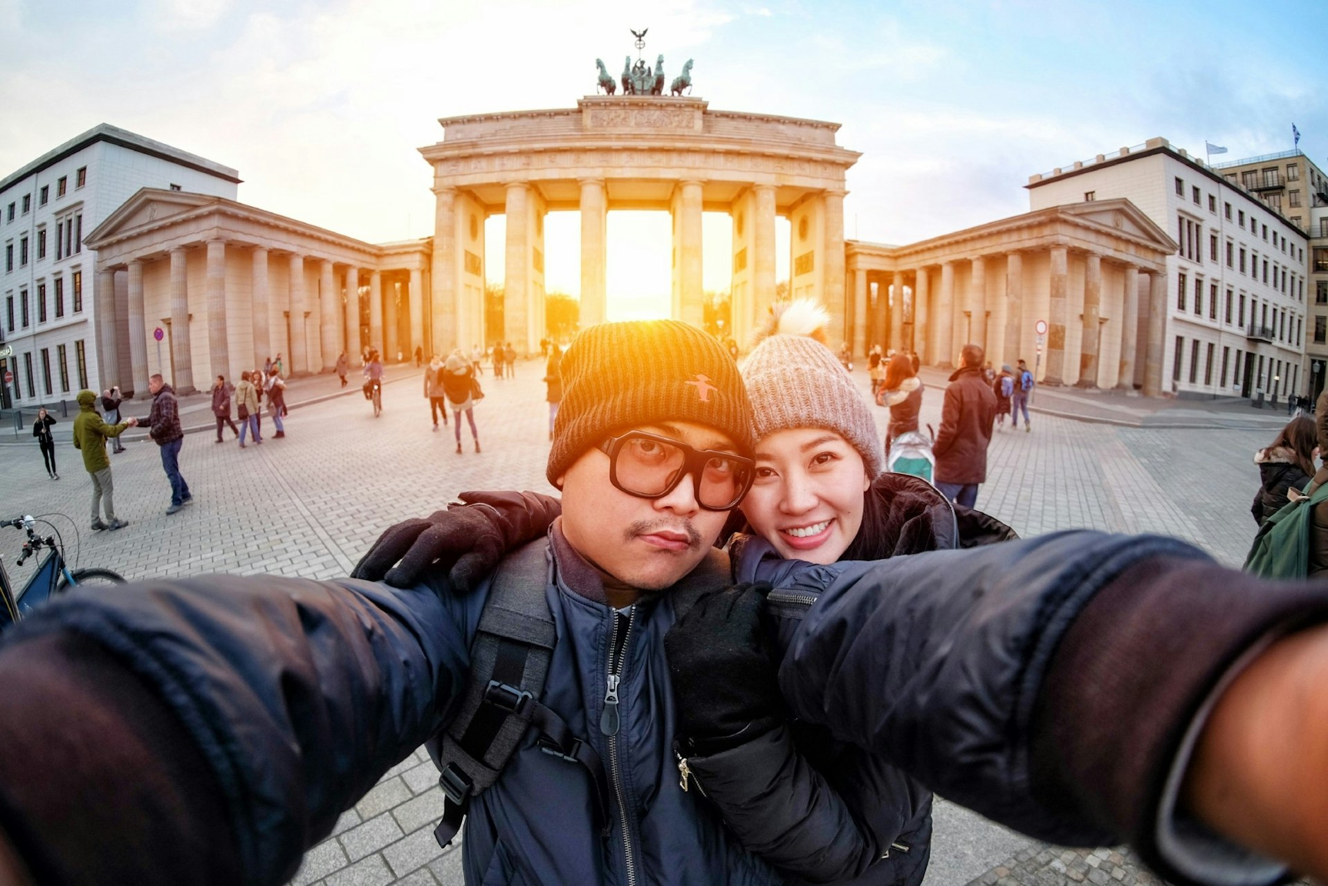 Young couple take a selfie with a smartphone at the Brandenburg Gate in sunlight, the famous landmark of Berlin