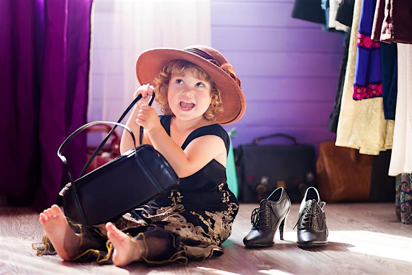 Kids Blog - shutterstock_754252606 A young child plays dress up, wearing a hat and holding a handbag © Alina Demidenko / Shutterstock