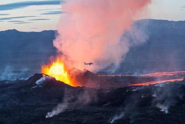 A small plane flies over the volatile mouth of Holuhraun.