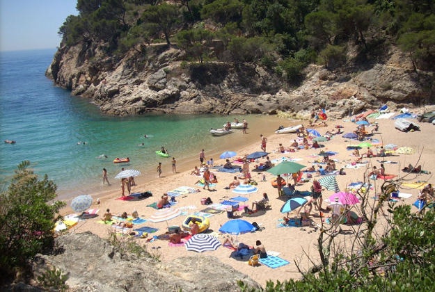 Tourists hit the beach in Tossa de Mar, Spain.