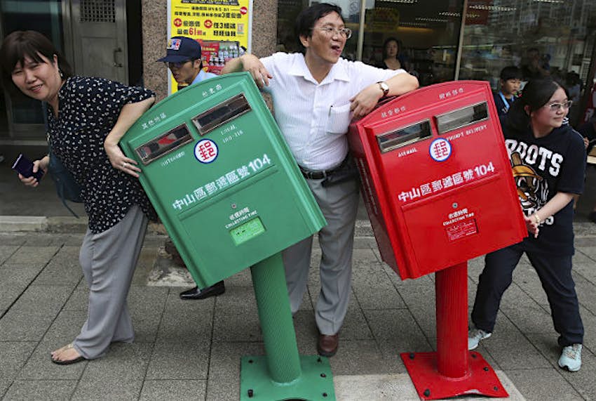 Travel News - taiwan typhoon postboxes 2 People pose for photographs next to a pair of roadside mailboxes that were uniformly bent by a falling signboard during Typhoon Soudelor earlier this month in Taipei, Taiwan. The damaged mailboxes have become celebrities in Taiwan.